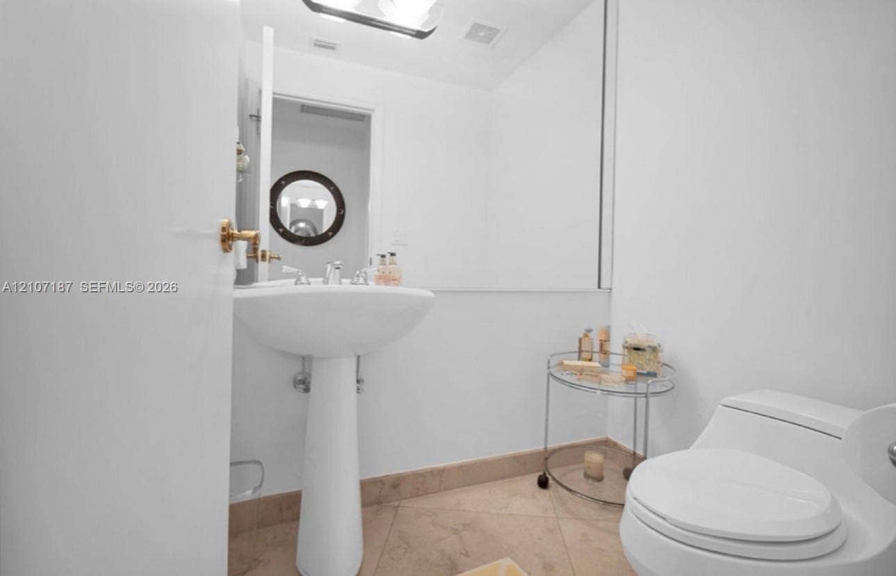 9601 Collins Avenue, #403, Bal Harbour, FL 33154 Pedestal sink with polished metal faucet, large wall-mounted mirror, and tile flooring