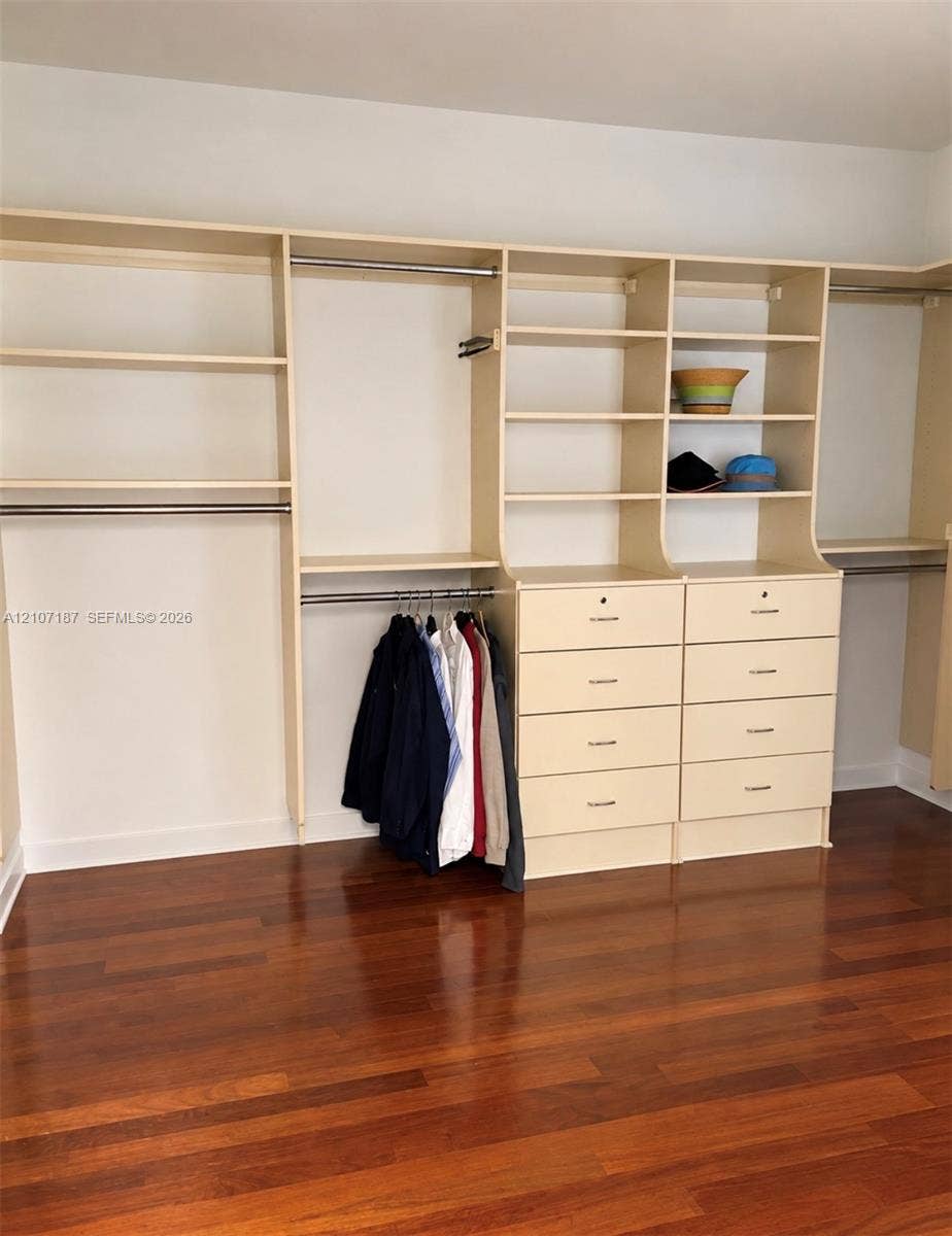 9601 Collins Avenue, #403, Bal Harbour, FL 33154 Custom walk-in closet featuring extensive built-in shelving, hanging rods, multi-drawer storage, and wood-finish flooring