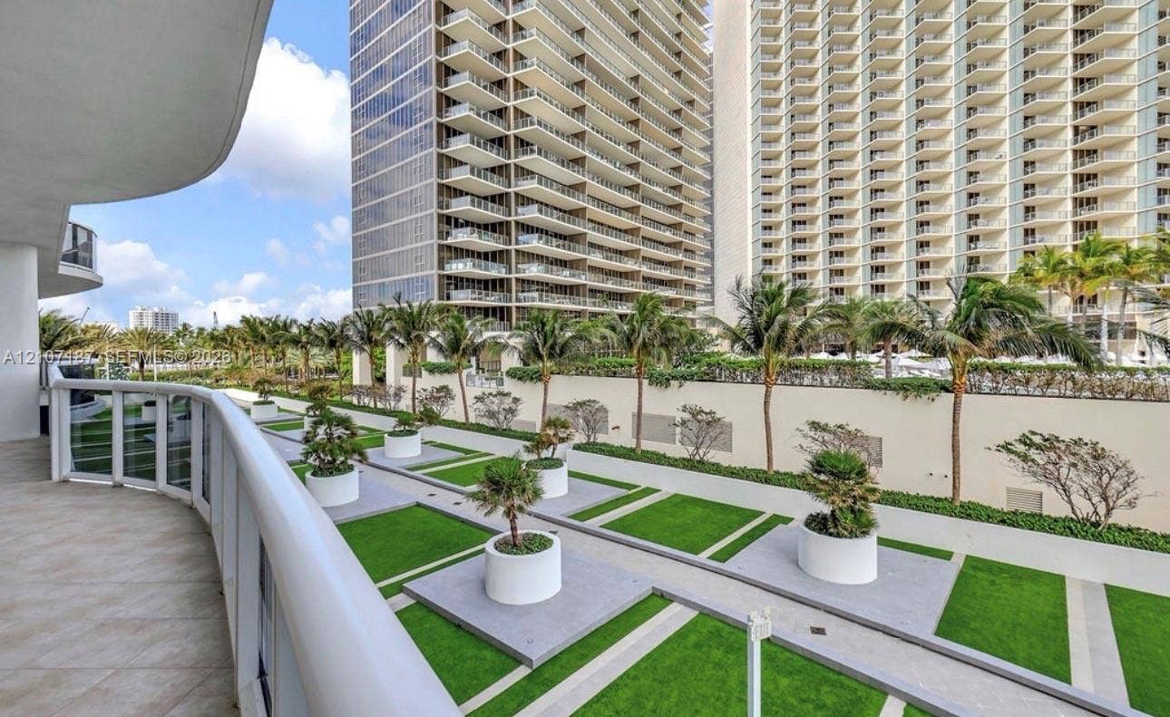 9601 Collins Avenue, #403, Bal Harbour, FL 33154 Private balcony featuring tile flooring, glass railing, and a geometric landscaped terrace with container plantings and paved pathways