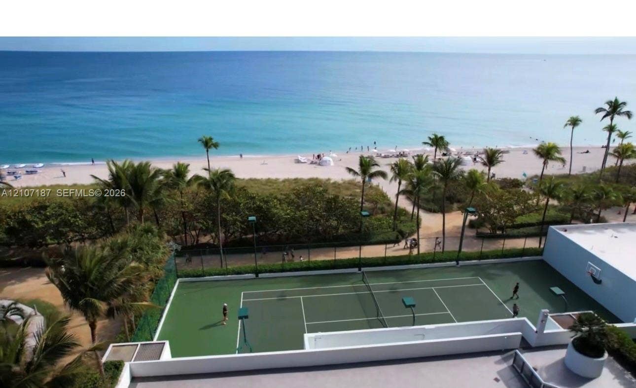 9601 Collins Avenue, #403, Bal Harbour, FL 33154 Tennis court featuring a hard surface, perimeter fencing, and integrated lighting fixtures, situated on the oceanfront