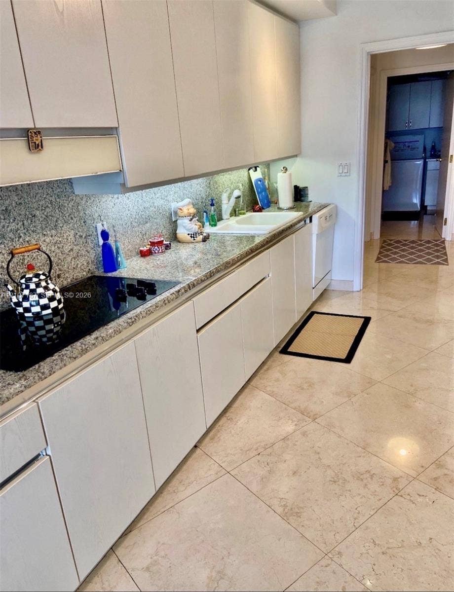 9601 Collins Avenue, #403, Bal Harbour, FL 33154 Kitchen featuring flat-panel cabinetry, stone-finish countertops, integrated cooktop, undermount sink, and large-format tile flooring