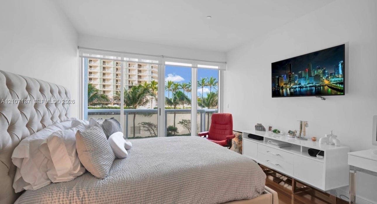 9601 Collins Avenue, #403, Bal Harbour, FL 33154 Floor-to-ceiling sliding glass doors with roller shades and wood-finish flooring