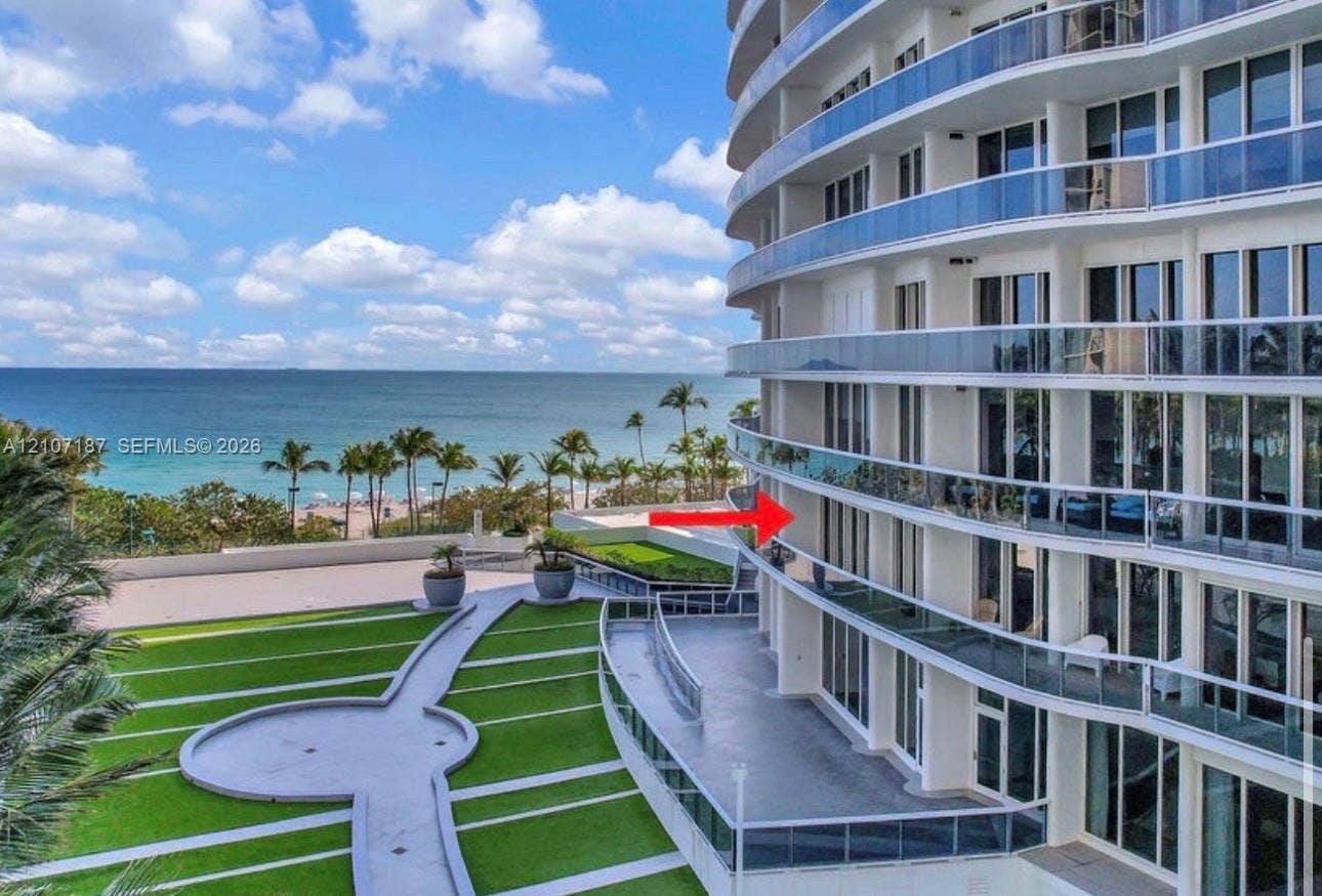 9601 Collins Avenue, #403, Bal Harbour, FL 33154 High-rise exterior featuring curved glass-railing balconies, floor-to-ceiling windows, and landscaped grounds with paved walking paths