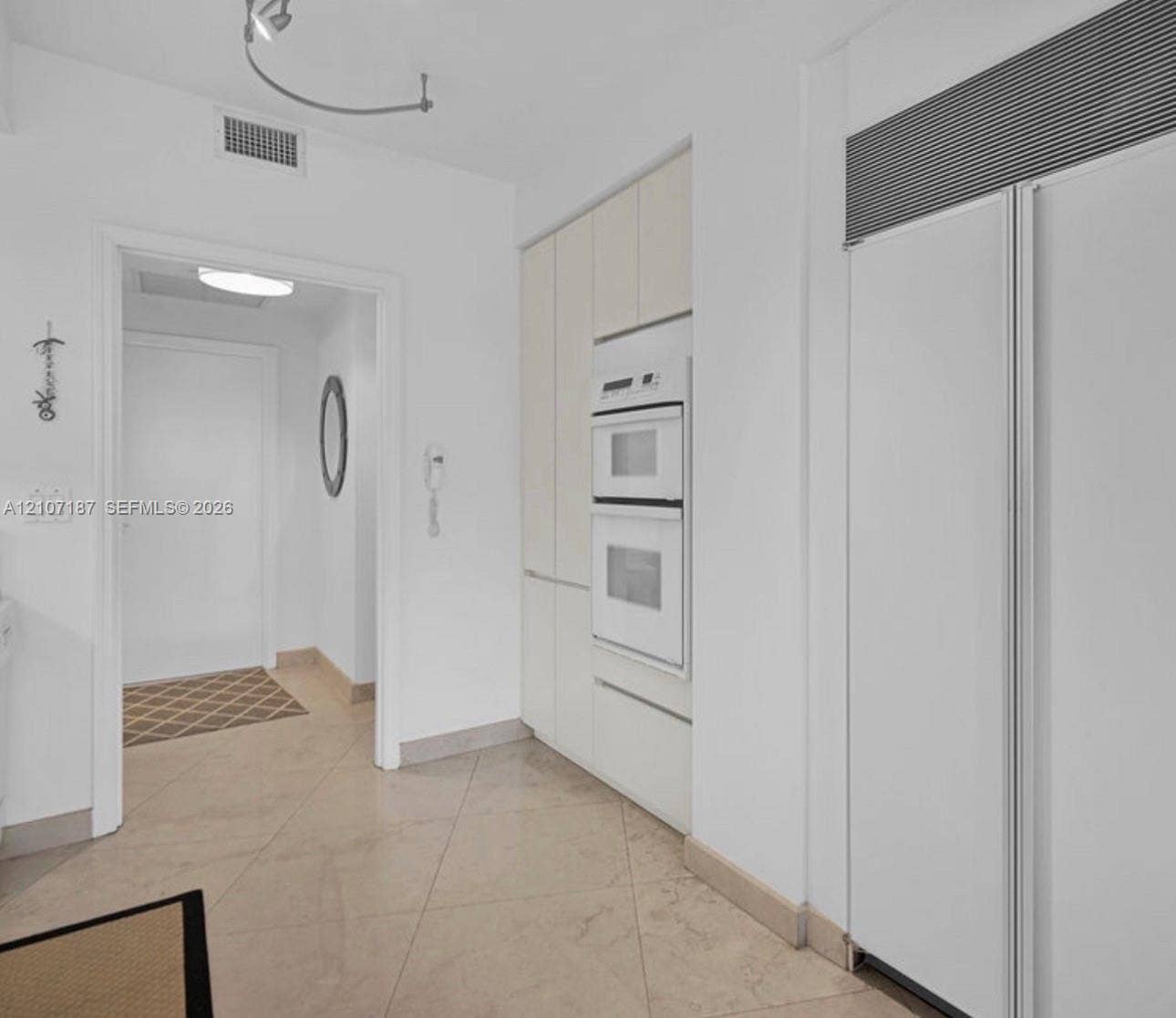 9601 Collins Avenue, #403, Bal Harbour, FL 33154 Built-in double wall oven, integrated panel-ready refrigerator, and custom flat-panel cabinetry, complemented by oversized ceramic floor tiling