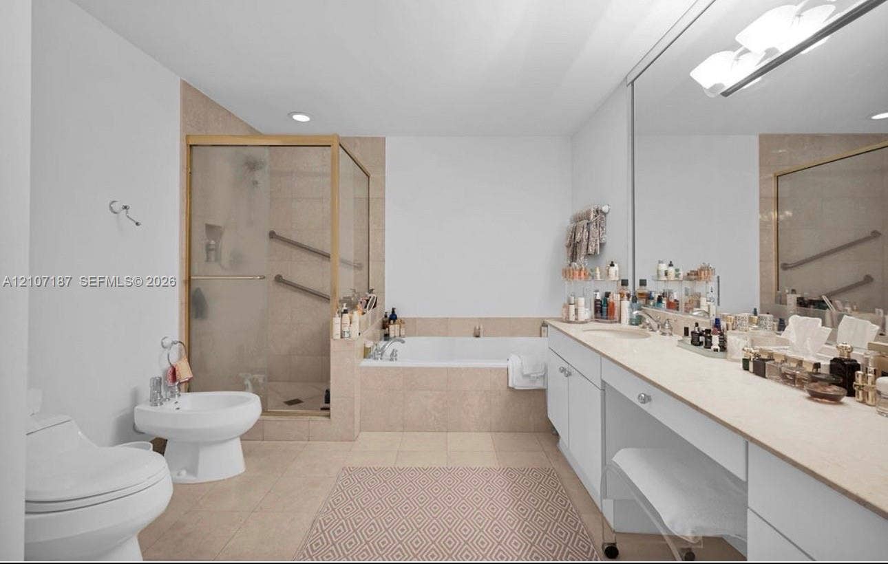 9601 Collins Avenue, #403, Bal Harbour, FL 33154 Bathroom featuring a dual-sink vanity with light-toned countertops, a glass-enclosed shower, a separate soaking tub with tiled surround, and a bidet