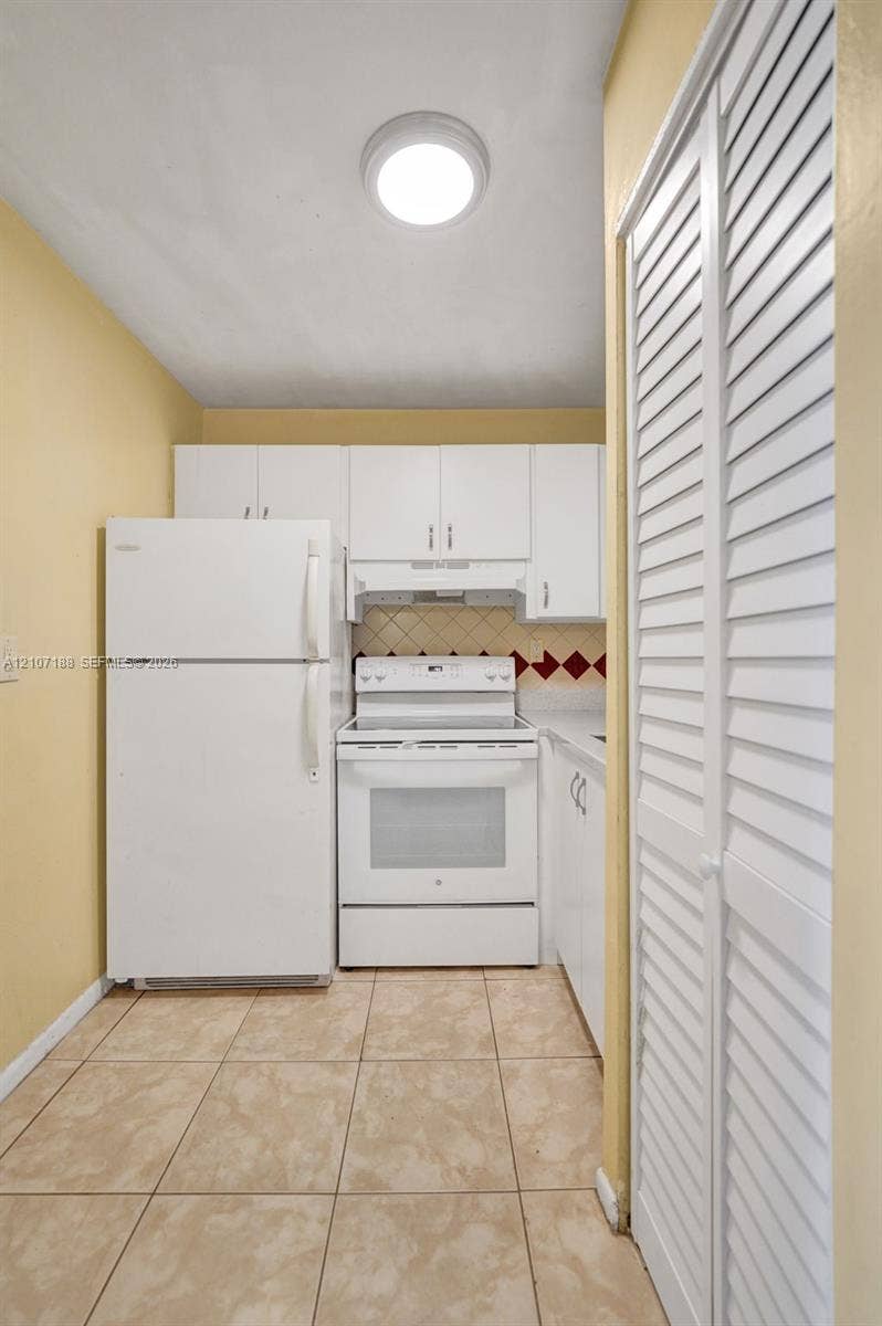 10301 NW 36th Street, #2, Coral Springs, Coral Springs, FL 33065 Kitchen featuring white cabinetry, an electric range, a top-freezer refrigerator, tiled flooring, and louvered bi-fold doors