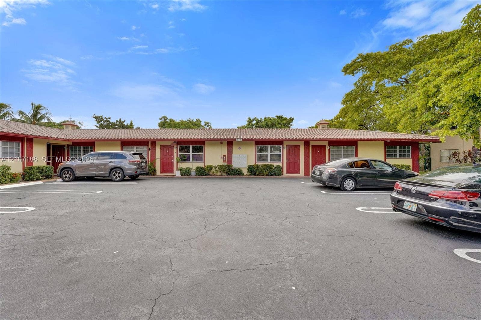 10301 NW 36th Street, #2, Coral Springs, Coral Springs, FL 33065 Single-story exterior featuring a low-pitch tile roof, painted stucco facade, red entry doors, and dedicated asphalt parking