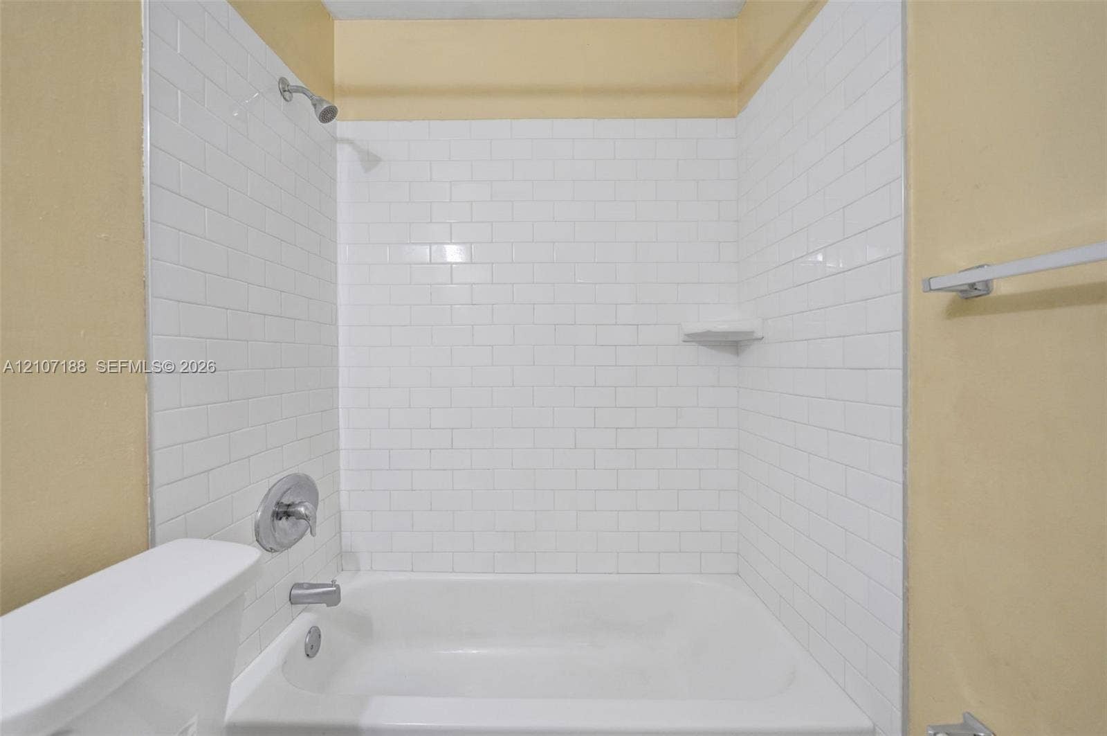 10301 NW 36th Street, #2, Coral Springs, Coral Springs, FL 33065 Bathtub enclosure featuring white subway tile surround, integrated soap dish, chrome shower head, and chrome mixing valve