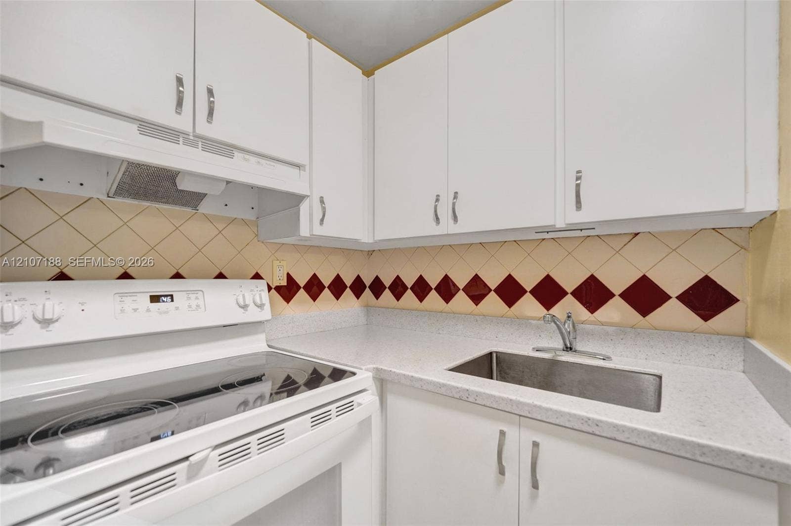 10301 NW 36th Street, #2, Coral Springs, Coral Springs, FL 33065 Kitchen featuring white cabinetry, solid-surface countertops, a stainless steel undermount sink, and a range with a built-in ventilation hood