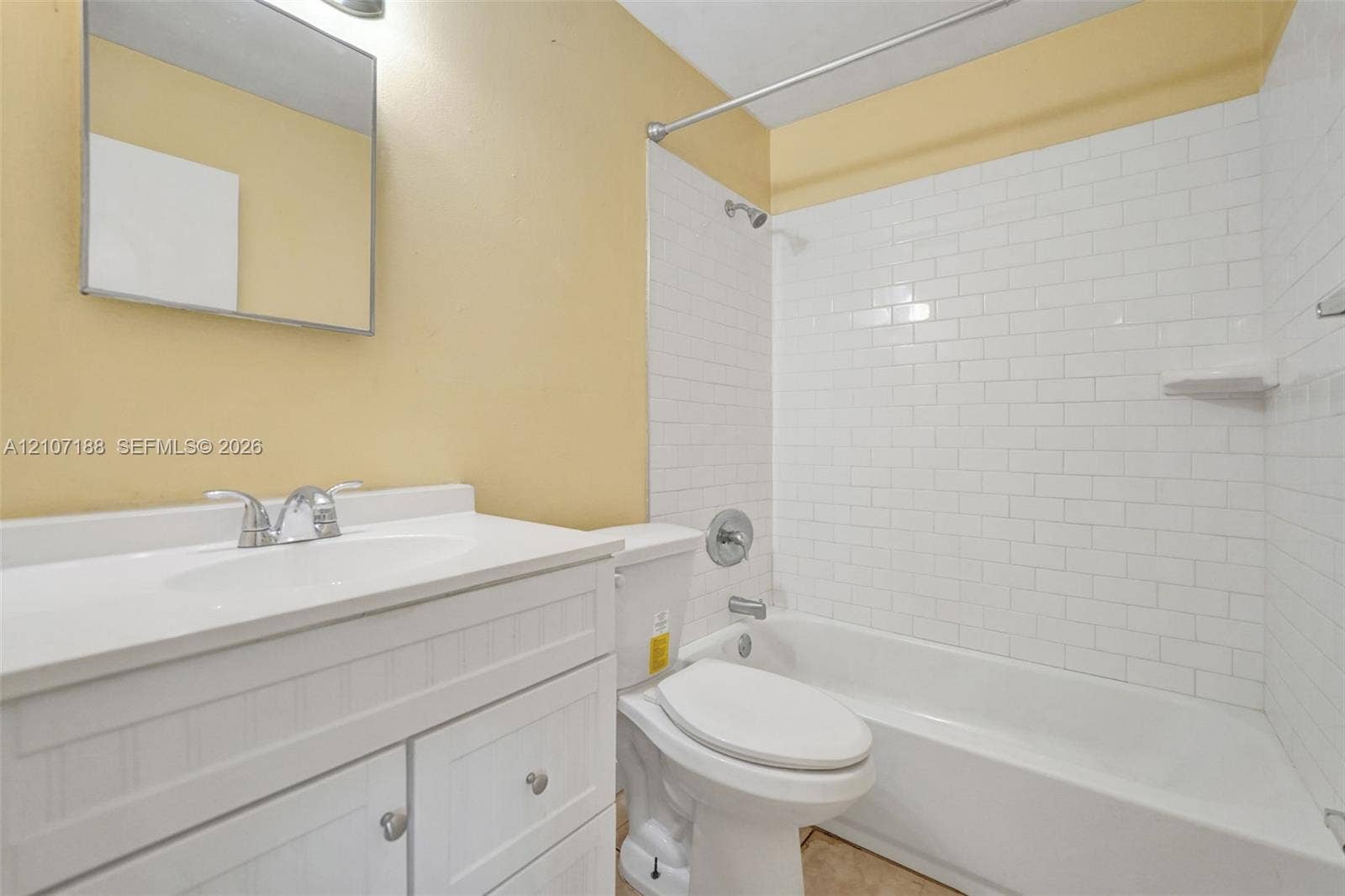 10301 NW 36th Street, #2, Coral Springs, Coral Springs, FL 33065 White vanity featuring a cabinet base, integrated basin, and polished chrome faucet, complemented by a subway-tiled tub enclosure and wall-mounted vanity mirror