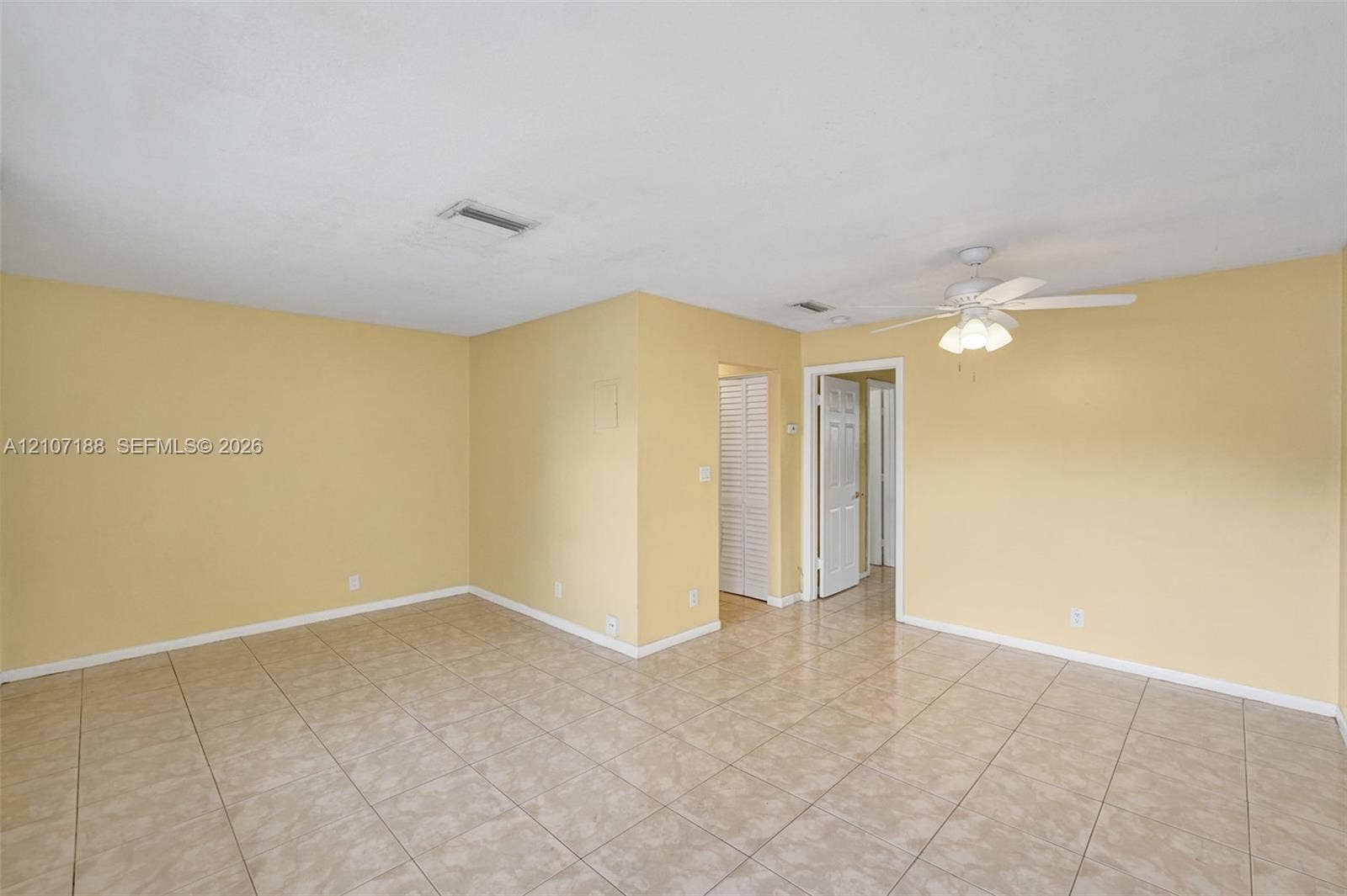10301 NW 36th Street, #2, Coral Springs, Coral Springs, FL 33065 Interior room featuring neutral-toned tile flooring, light-colored walls, a ceiling fan with integrated lighting, and louvered bifold closet doors