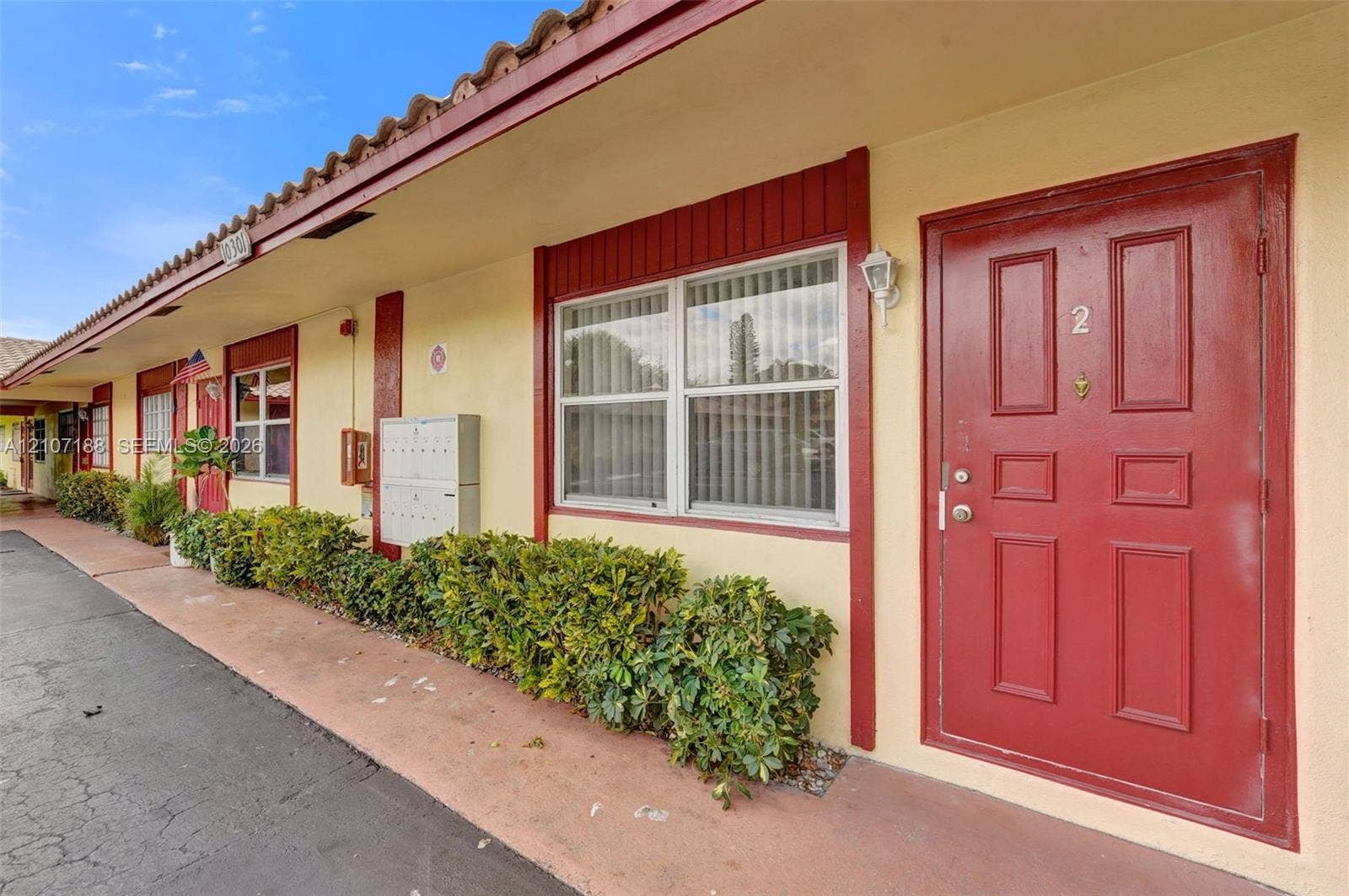 10301 NW 36th Street, #2, Coral Springs, Coral Springs, FL 33065 Stucco exterior featuring clay tile roof accents, red-toned paneled entry doors, and wall-mounted exterior lighting
