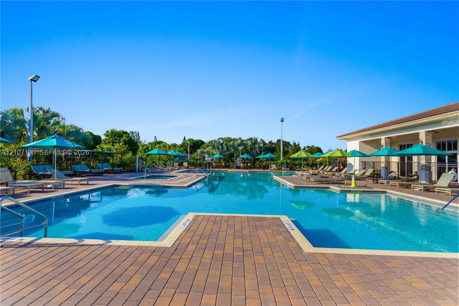 Swimming pool featuring a paver deck, integrated lap lanes, shallow sun shelf, and metal handrails