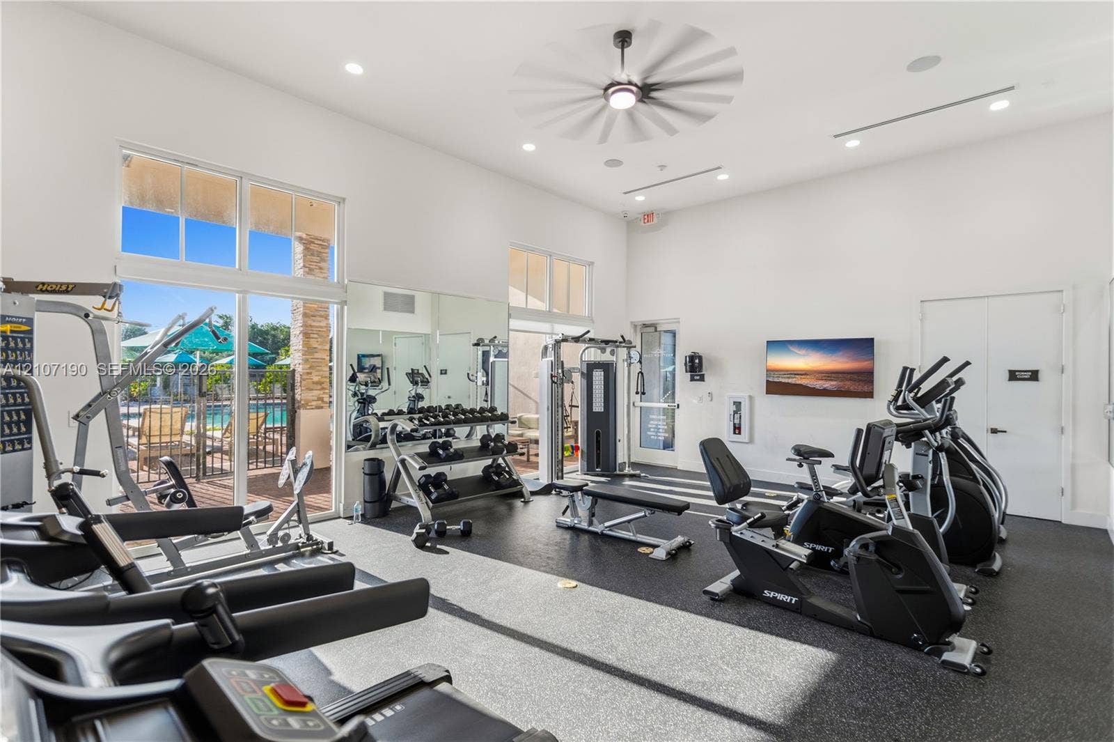 Fitness center featuring high ceilings, recessed lighting, full-wall mirrors, durable rubberized flooring, and large-pane windows