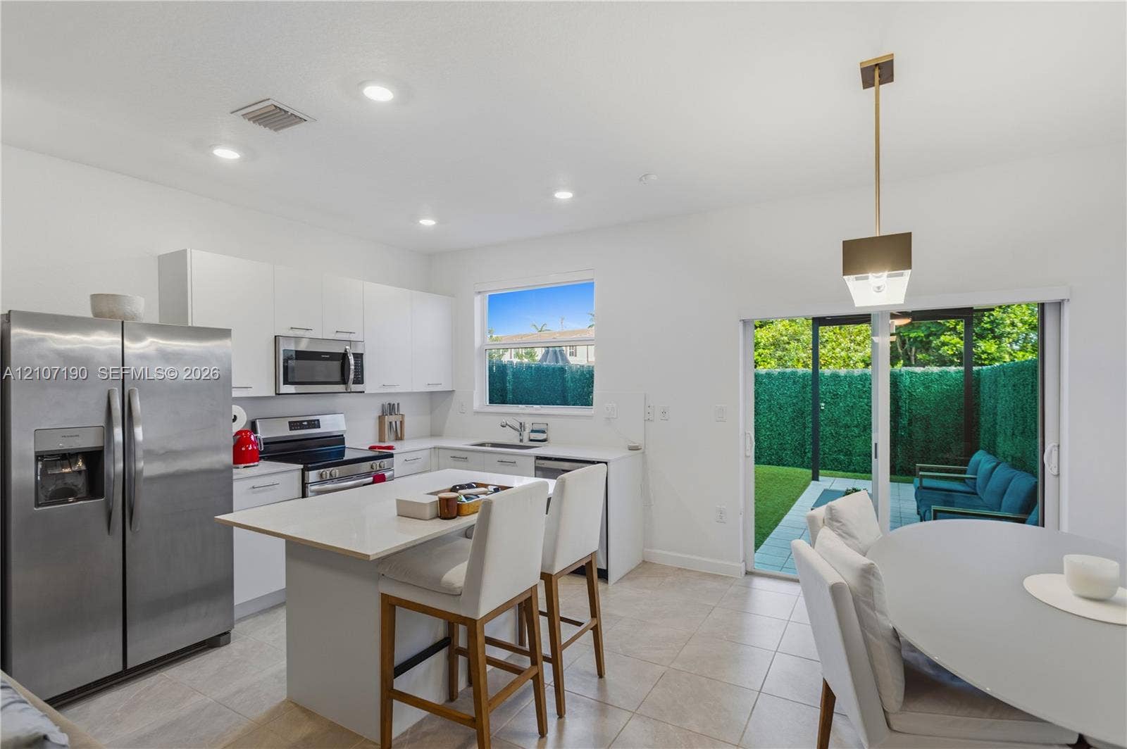 Kitchen featuring white cabinetry, solid-surface countertops, center island, stainless steel appliances, and sliding glass doors