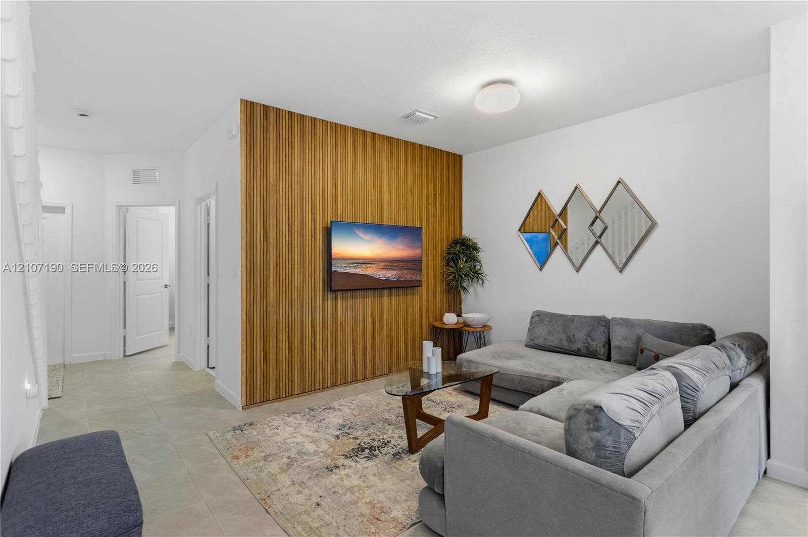 Interior space featuring a floor-to-ceiling wood-slat accent wall, neutral large-format tile flooring, and a low-profile flush-mount ceiling light fixture