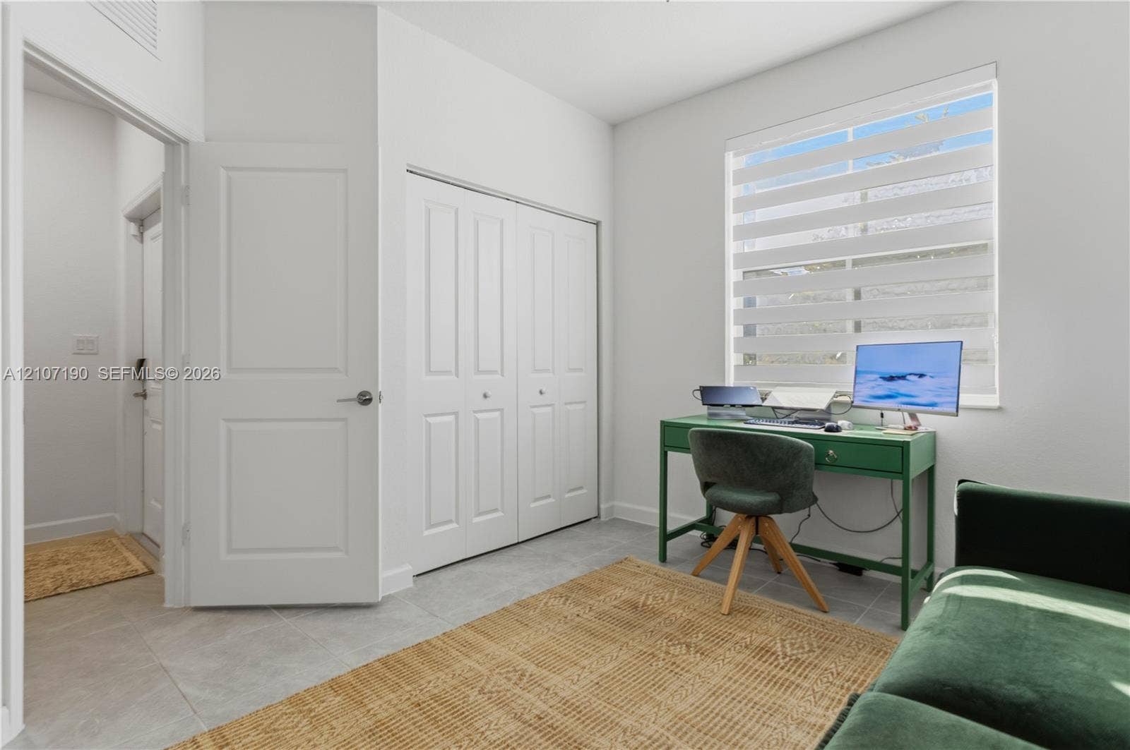 Room featuring light-toned tile flooring, dual-panel interior doors, a double-door closet with recessed hardware, and a window equipped with banded light-filtering shades