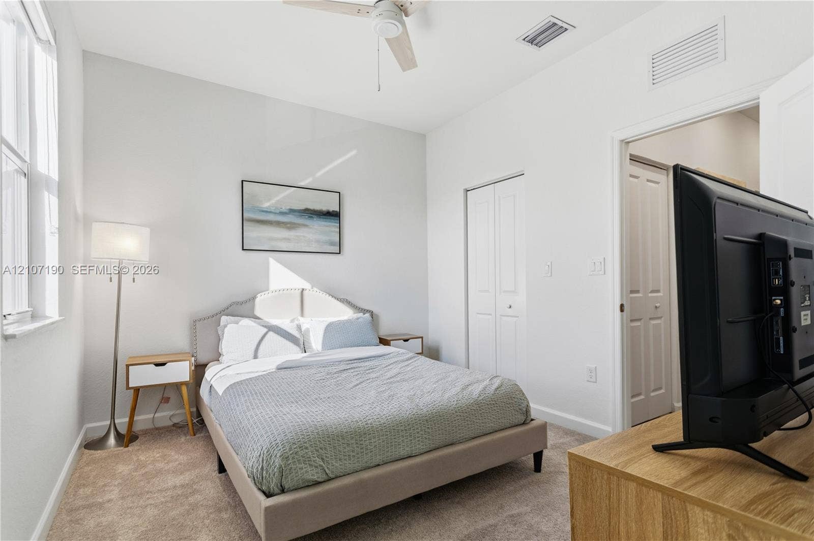 Bedroom featuring neutral carpeting, a ceiling fan, and double-door closet storage