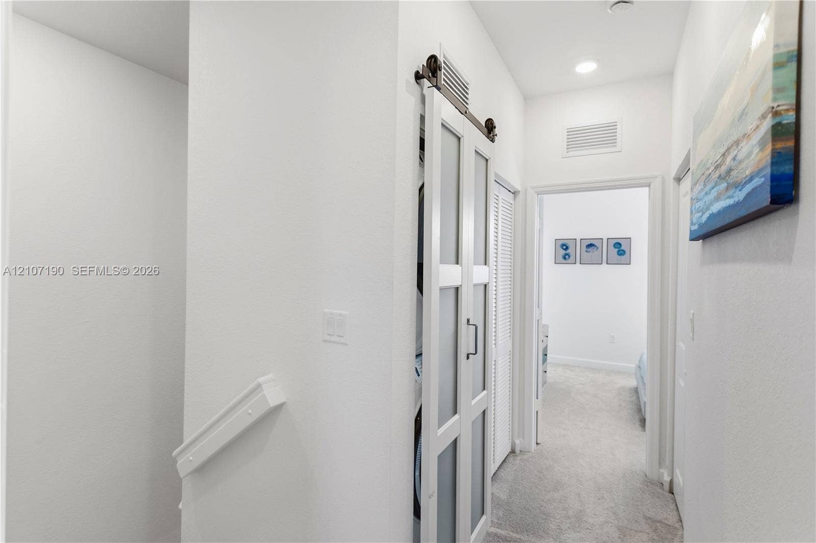 Frosted glass sliding barn door with dark hardware, recessed lighting, and wall-to-wall carpeting