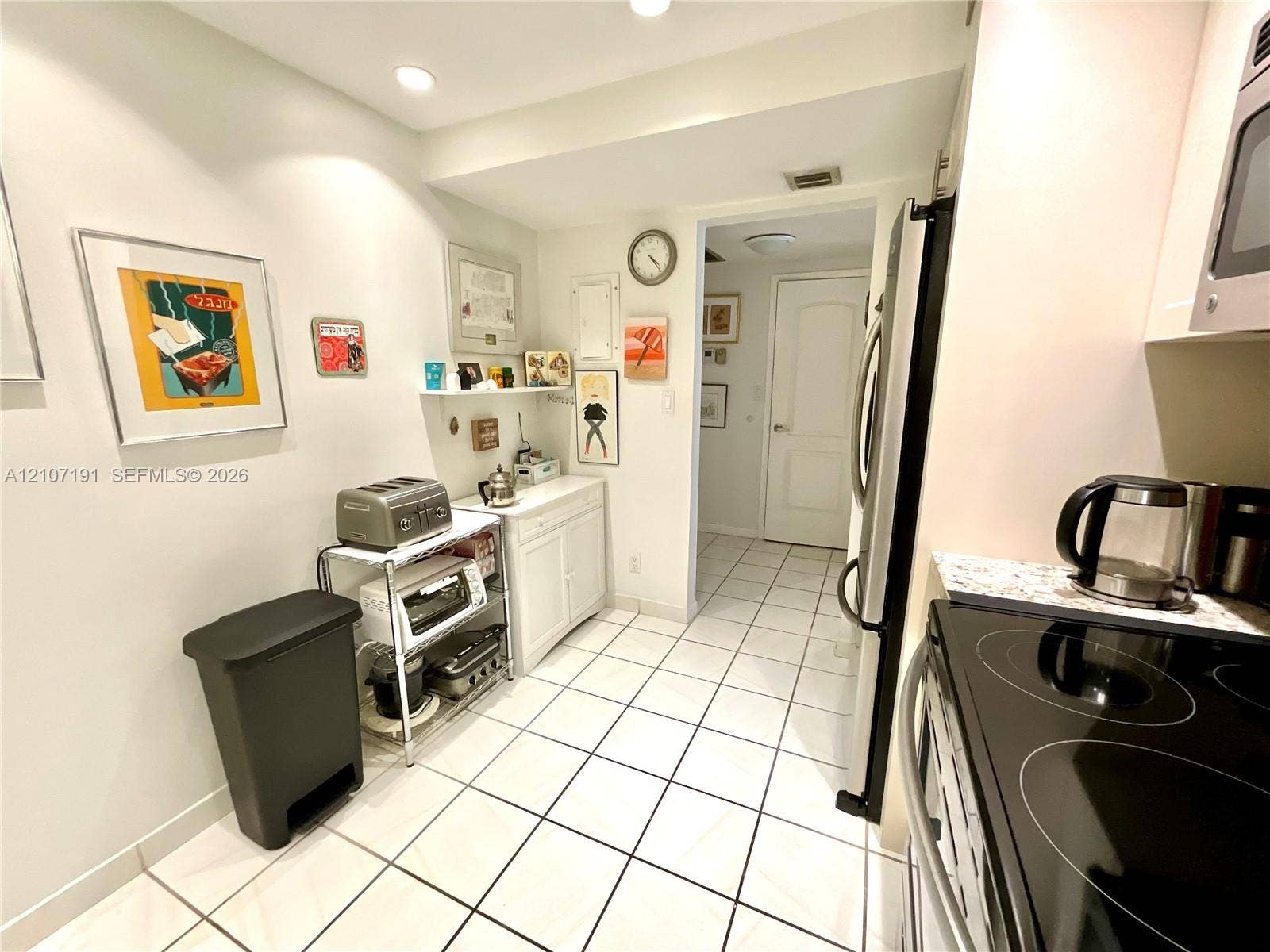Kitchen featuring white cabinetry, stone-finish countertops, stainless steel appliances, ceramic tile flooring, and recessed lighting