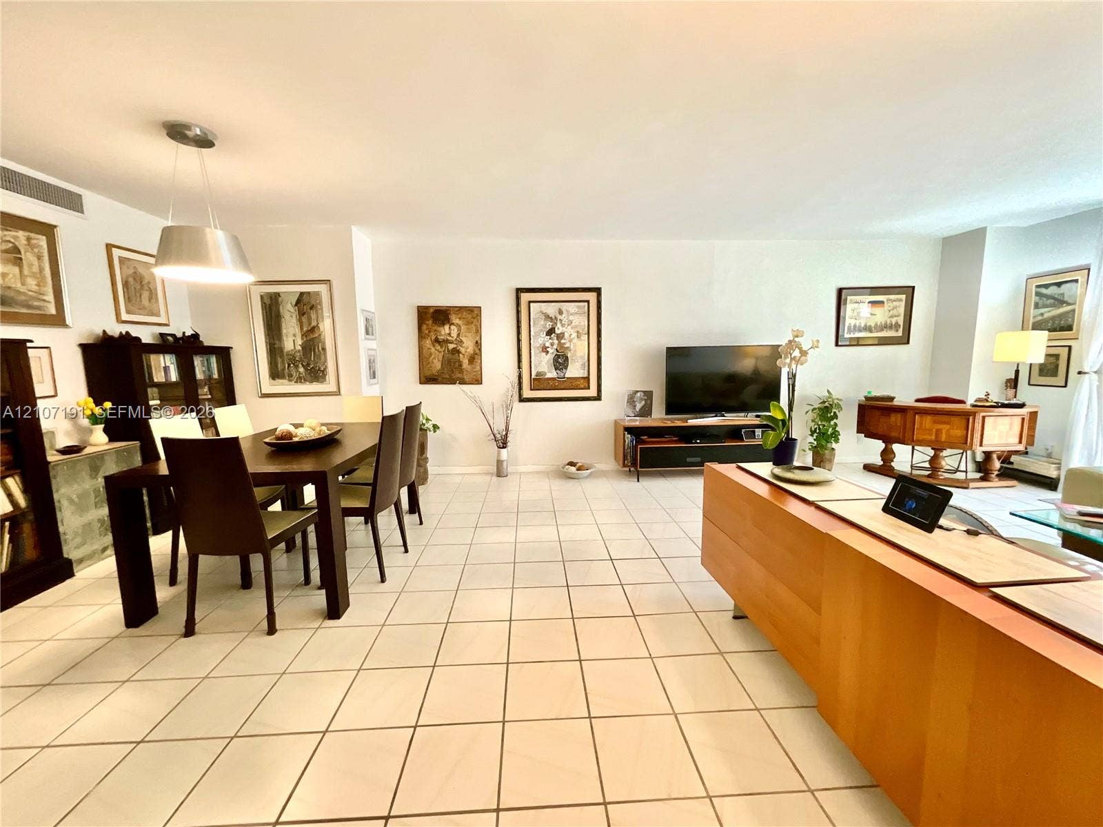 Open-concept interior featuring large-format ceramic tile flooring, neutral wall finishes, and a modern drum-style pendant light fixture