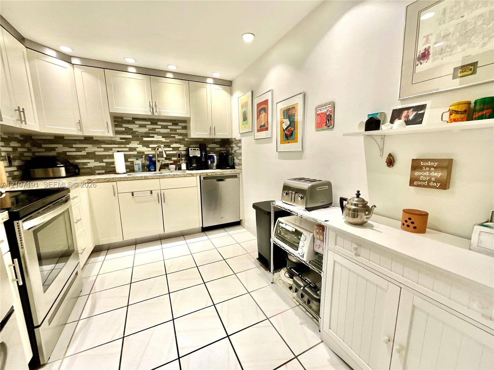 Kitchen featuring white cabinetry, stone-finish countertops, tile backsplash, stainless steel dishwasher, and ceramic tile flooring