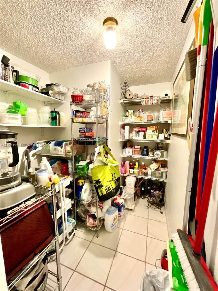 Storage area featuring multi-tiered fixed shelving and tiled flooring