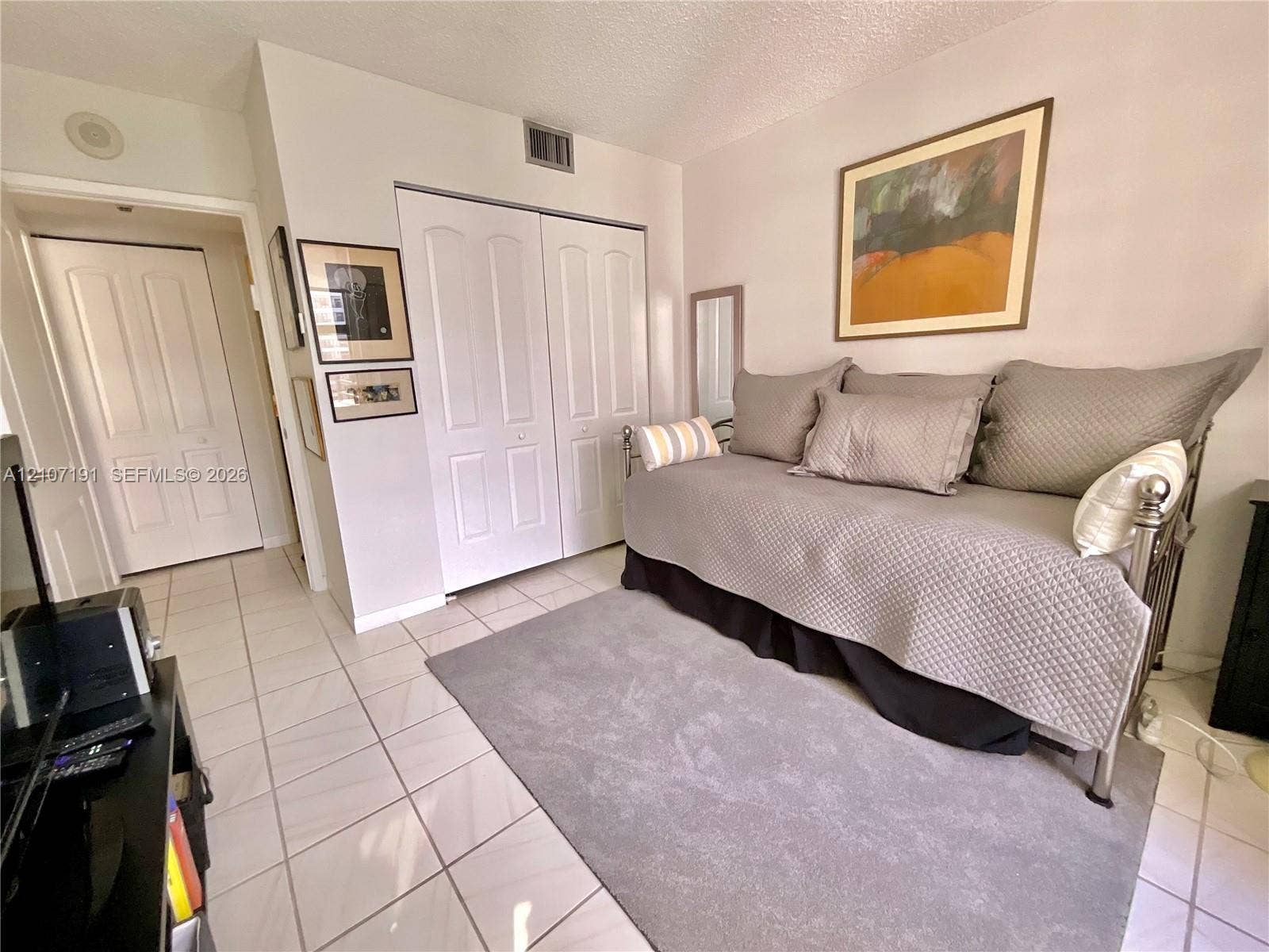 Neutral ceramic tile flooring and white paneled closet doors