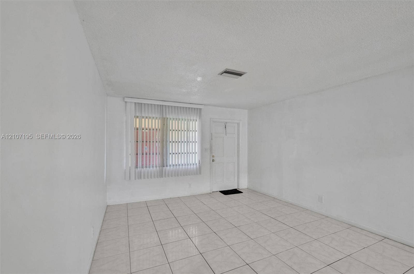 10301 NW 36th Street, #5, Coral Springs, Coral Springs, FL 33065 Interior space featuring light-toned ceramic tile flooring, vertical window blinds, and a solid-panel door