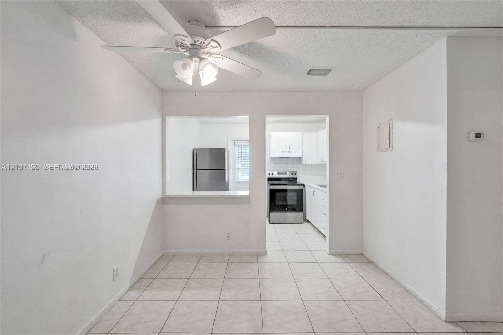 10301 NW 36th Street, #5, Coral Springs, Coral Springs, FL 33065 Ceramic tile flooring, white cabinetry, stainless steel kitchen appliances, and ceiling fan with integrated lighting
