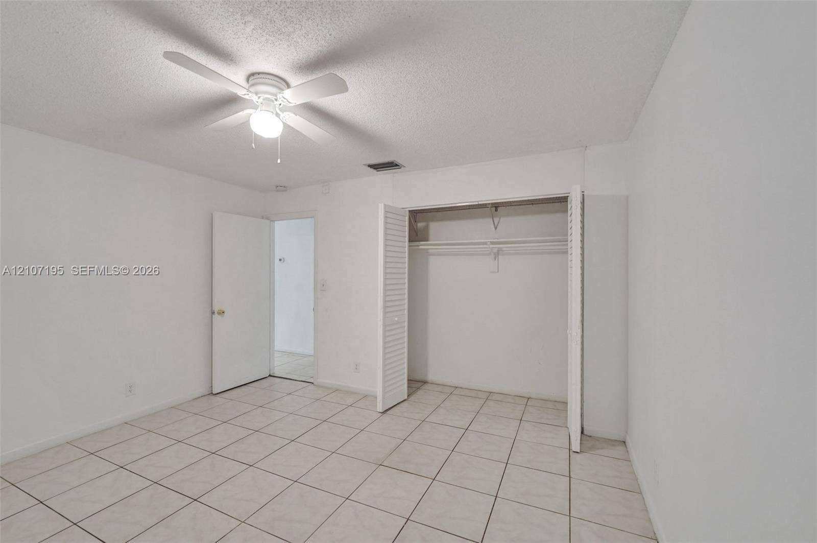 10301 NW 36th Street, #5, Coral Springs, Coral Springs, FL 33065 Neutral room featuring square tile flooring, a ceiling fan with integrated lighting, and a closet with louvered bifold doors