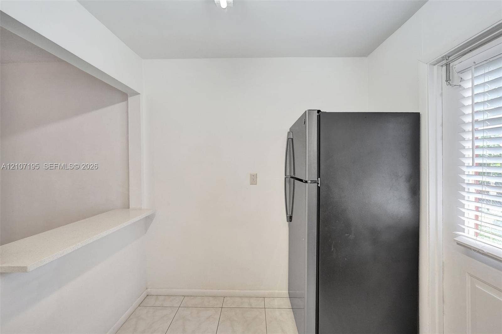 10301 NW 36th Street, #5, Coral Springs, Coral Springs, FL 33065 Built-in pass-through ledge, stainless steel refrigerator, white tile flooring, and window with fitted horizontal blinds