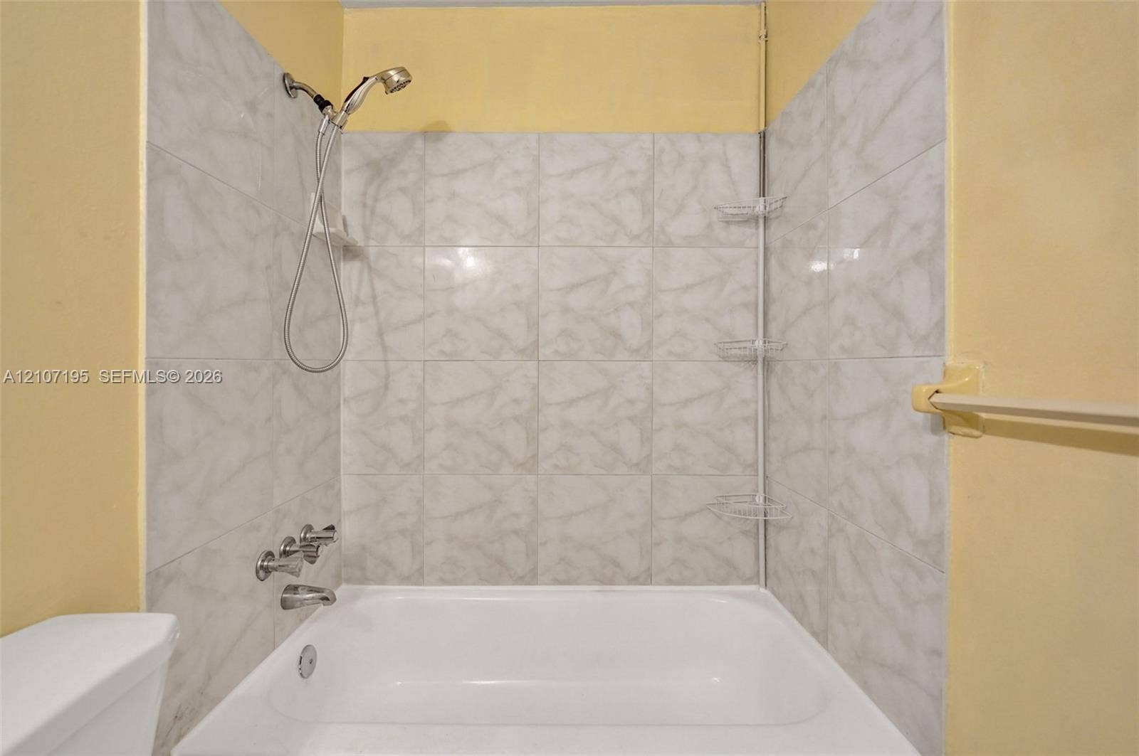 10301 NW 36th Street, #5, Coral Springs, Coral Springs, FL 33065 Shower and tub combination featuring light-toned tile surround, handheld shower head, chrome-finish faucet fixtures, and integrated wall-mounted shelving