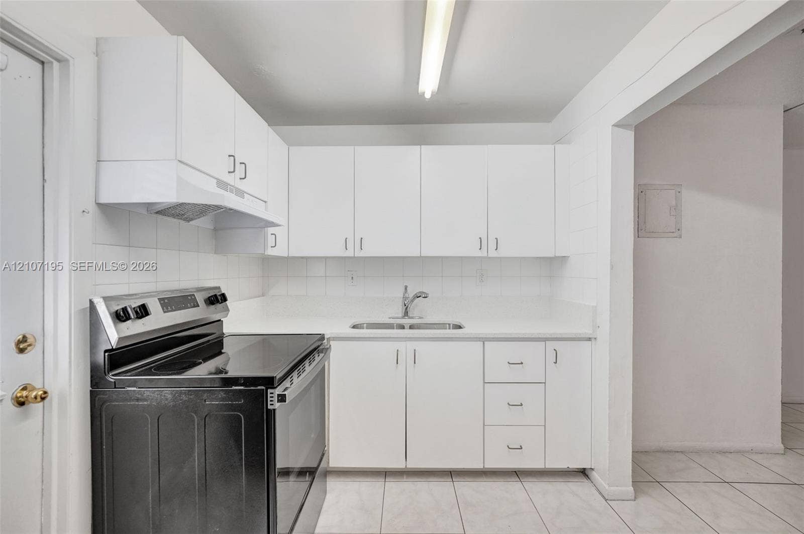 10301 NW 36th Street, #5, Coral Springs, Coral Springs, FL 33065 Kitchen featuring white cabinetry, solid-surface countertops, dual-basin stainless steel sink, tile backsplash, and a black electric range