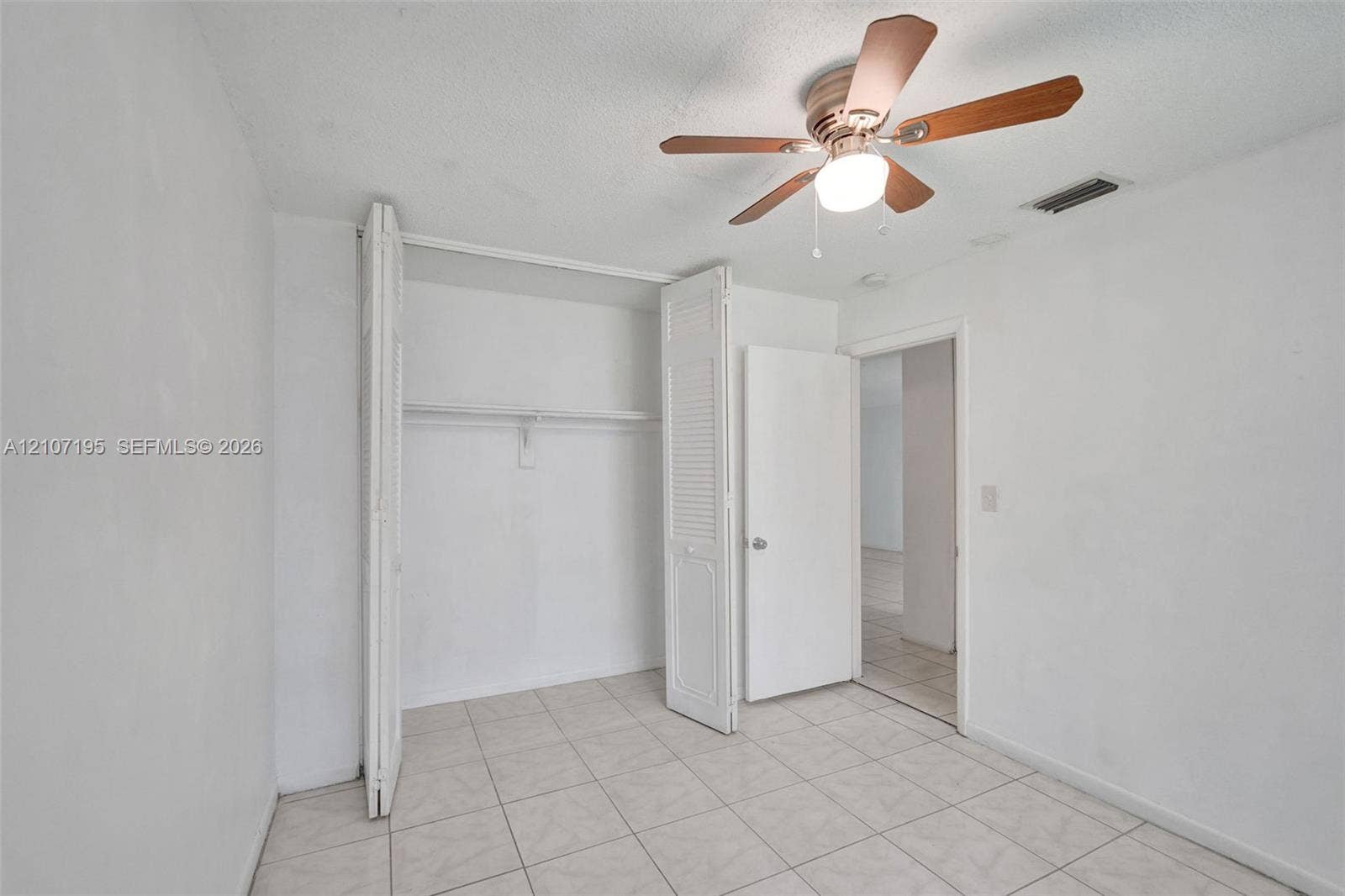 10301 NW 36th Street, #5, Coral Springs, Coral Springs, FL 33065 Room featuring light-colored tile flooring, a multi-blade ceiling fan with integrated lighting, and a closet with bifold louvered doors