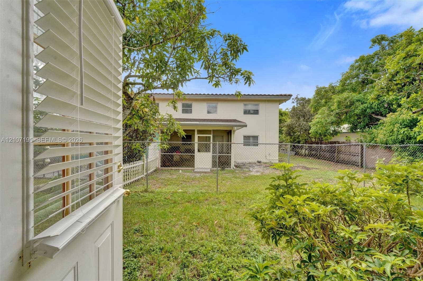 10301 NW 36th Street, #5, Coral Springs, Coral Springs, FL 33065 Backyard featuring a grass lawn, chain-link fencing, mature trees, and a screened-in rear porch