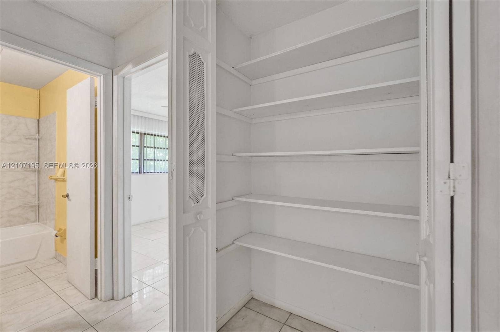 10301 NW 36th Street, #5, Coral Springs, Coral Springs, FL 33065 Built-in linen closet featuring multiple fixed shelving tiers and bi-fold doors with decorative inset detailing