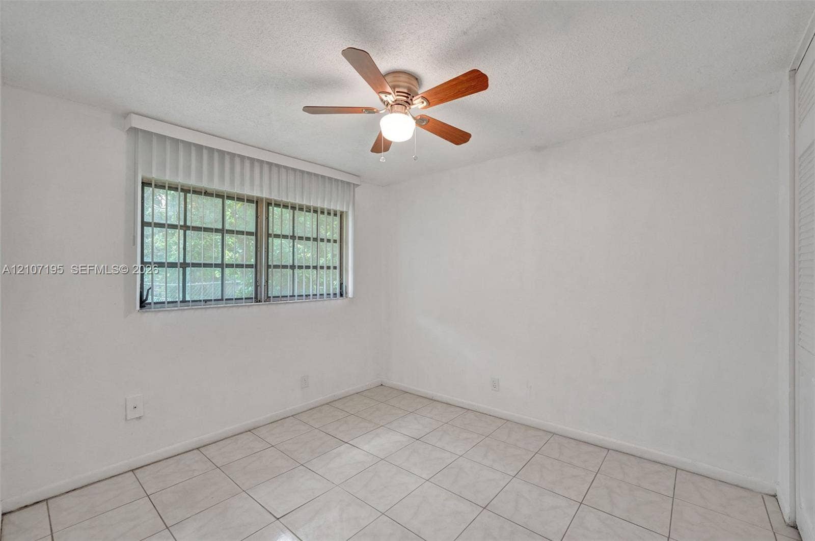 10301 NW 36th Street, #5, Coral Springs, Coral Springs, FL 33065 Room featuring white tile flooring, ceiling fan with light fixture, window with grid pattern, and vertical blinds