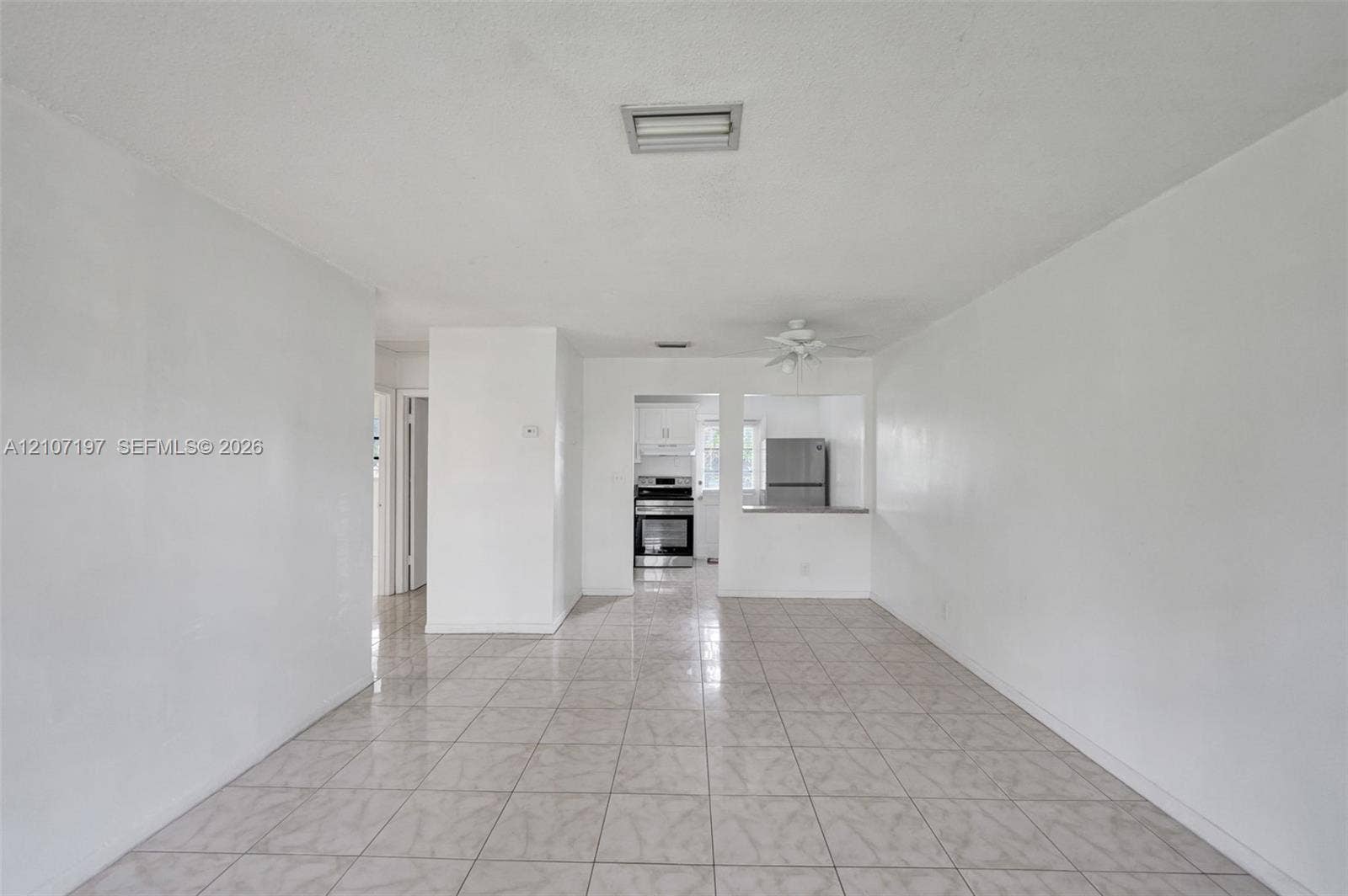 10301 NW 36th Street, #6, Coral Springs, Coral Springs, FL 33065 Open-concept interior featuring neutral tile flooring, white wall finishes, and a pass-through opening to the kitchen