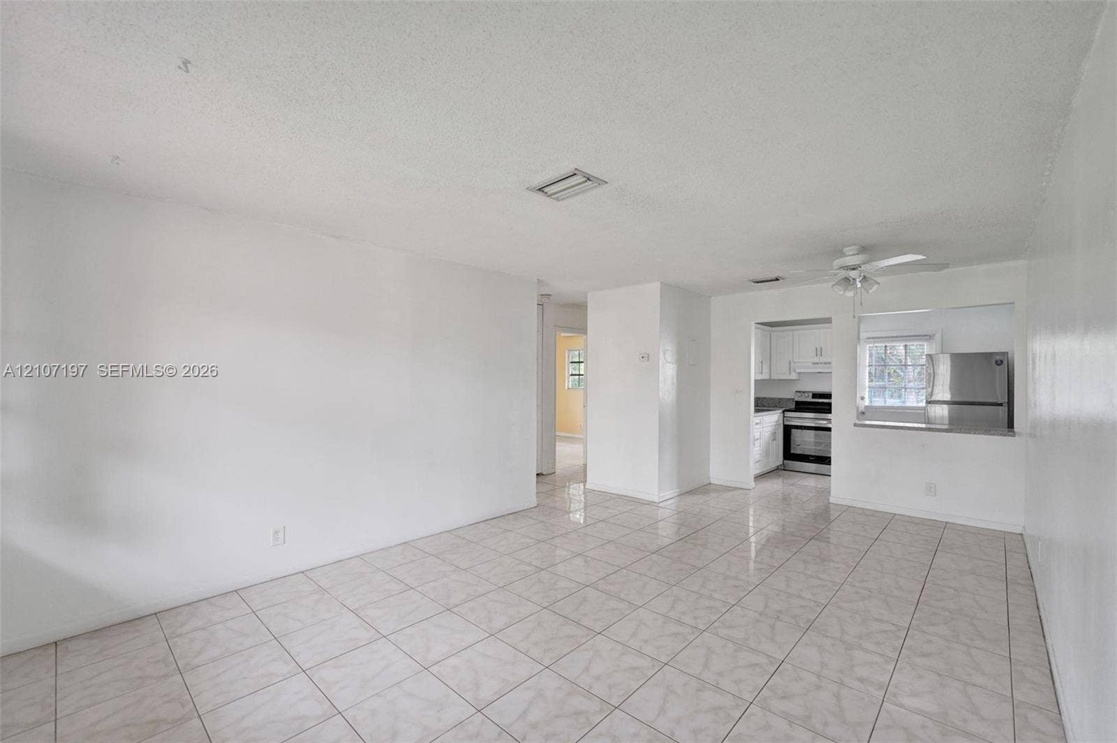 10301 NW 36th Street, #6, Coral Springs, Coral Springs, FL 33065 Interior space featuring neutral wall tones, ceramic tile flooring, ceiling fan with integrated lighting, and a kitchen pass-through