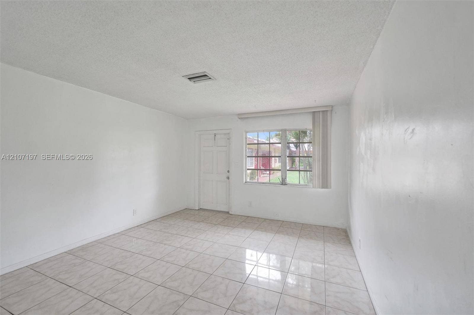 10301 NW 36th Street, #6, Coral Springs, Coral Springs, FL 33065 Interior space featuring large-format neutral floor tiling, textured ceiling finish, and a multipane window with vertical blinds