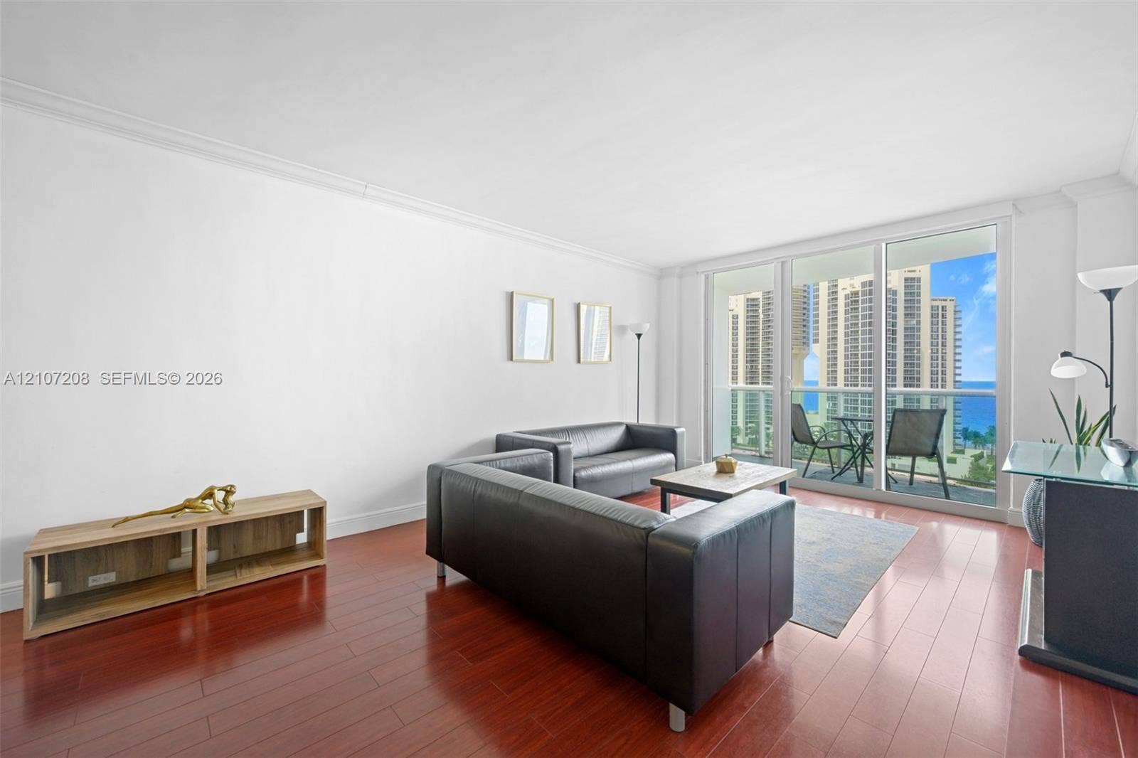 19370 Collins Avenue, #1405, Sunny Isles Beach, Sunny Isles Beach, FL 33160 Living area featuring wood-finish flooring, crown molding, and floor-to-ceiling glass sliding doors opening to a balcony