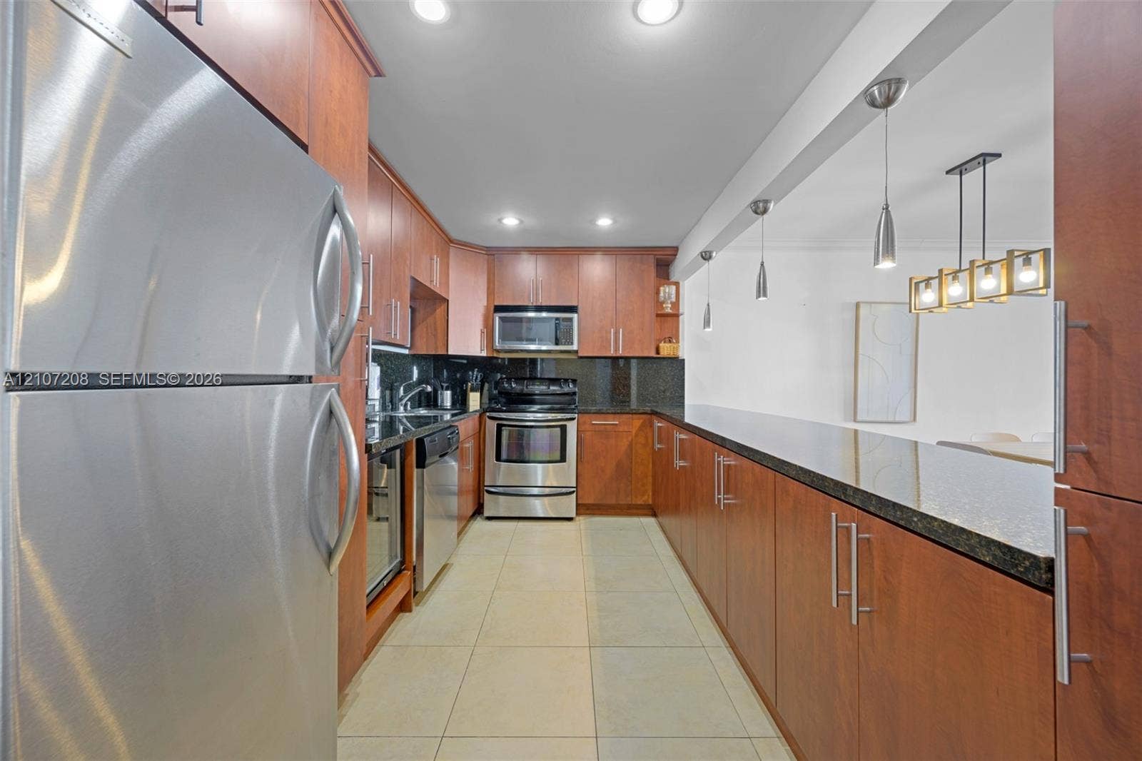 19370 Collins Avenue, #1405, Sunny Isles Beach, Sunny Isles Beach, FL 33160 Kitchen featuring stainless steel appliances, dark stone countertops, custom wood-finish cabinetry, ceramic tile flooring, and integrated pendant lighting