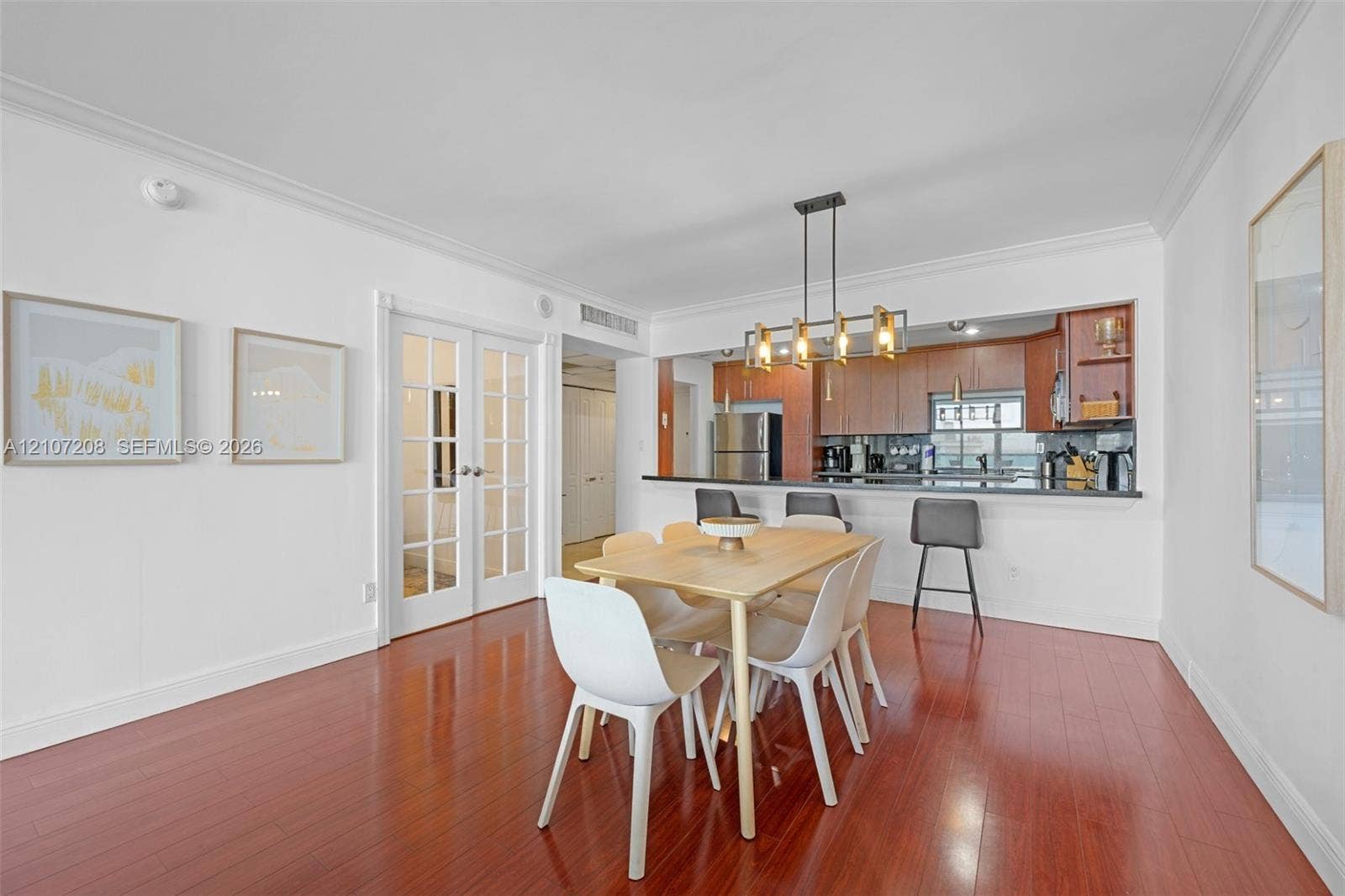 19370 Collins Avenue, #1405, Sunny Isles Beach, Sunny Isles Beach, FL 33160 Dining area featuring wood-finish flooring, crown molding, multi-pane French doors, and a linear multi-light chandelier