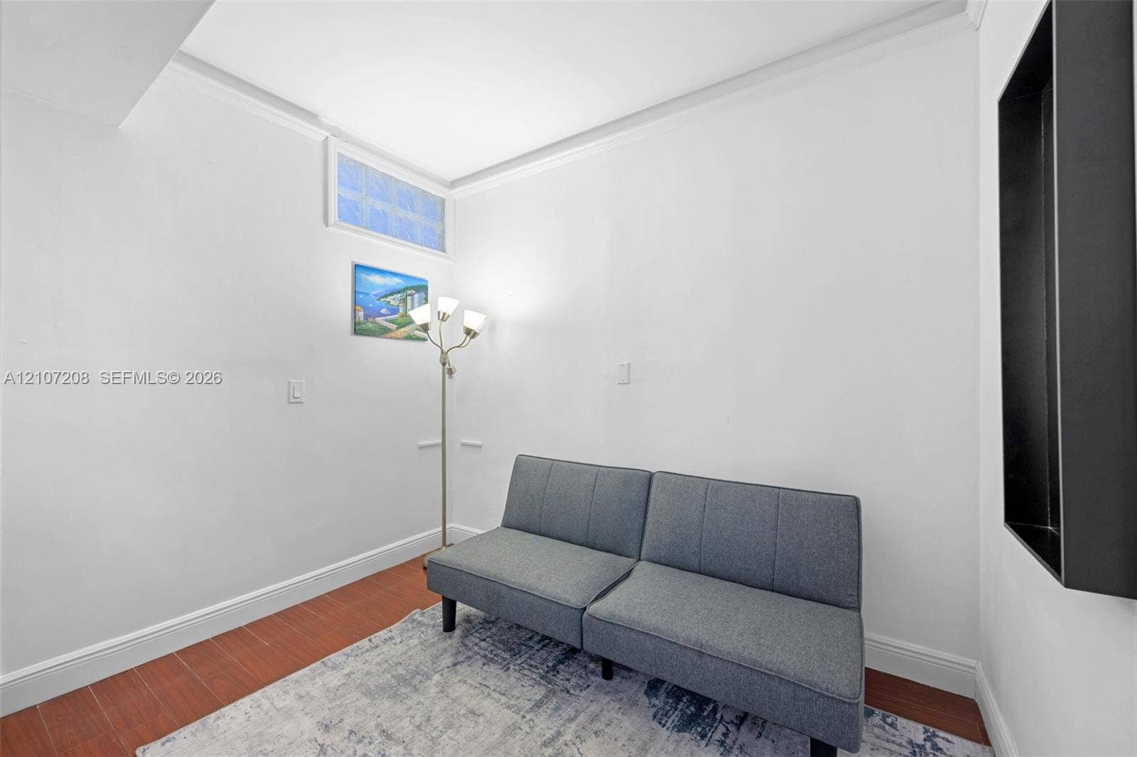 19370 Collins Avenue, #1405, Sunny Isles Beach, Sunny Isles Beach, FL 33160 Interior space featuring wood-finish flooring, crown molding, a high-set glass block window, and a recessed wall niche with a matte black frame