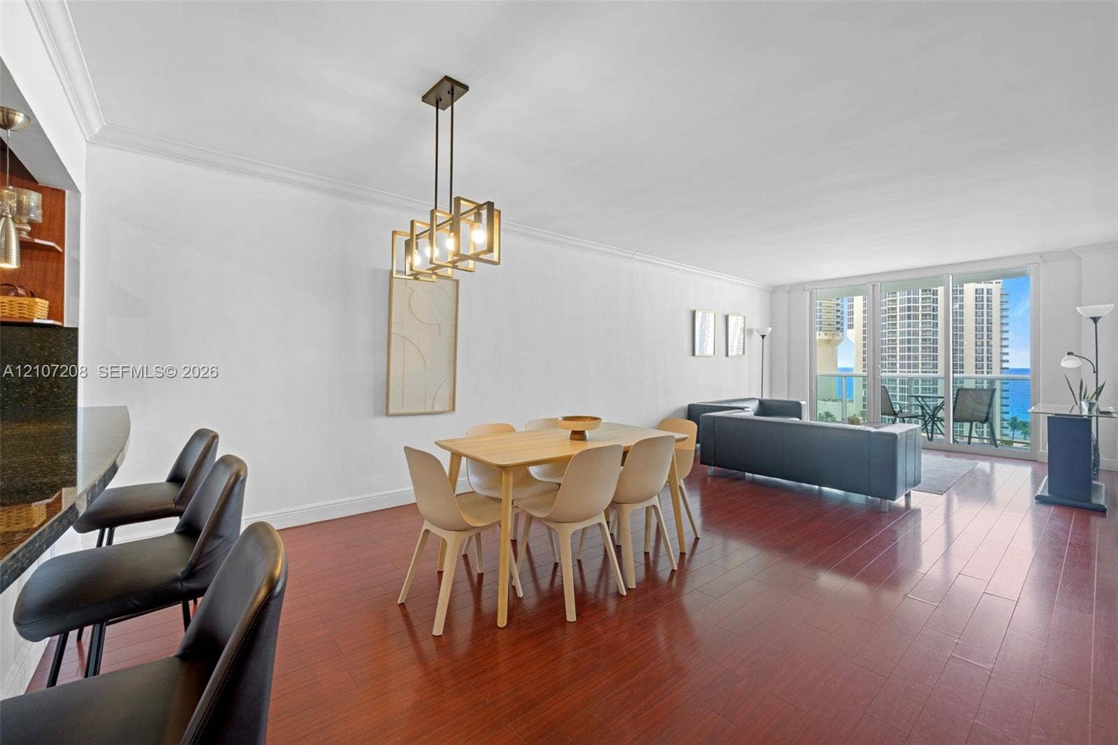 19370 Collins Avenue, #1405, Sunny Isles Beach, Sunny Isles Beach, FL 33160 Open-concept interior featuring wood-finish flooring, a kitchen breakfast bar with stone-finish countertop, geometric pendant lighting, and large sliding glass doors providing outdoor access