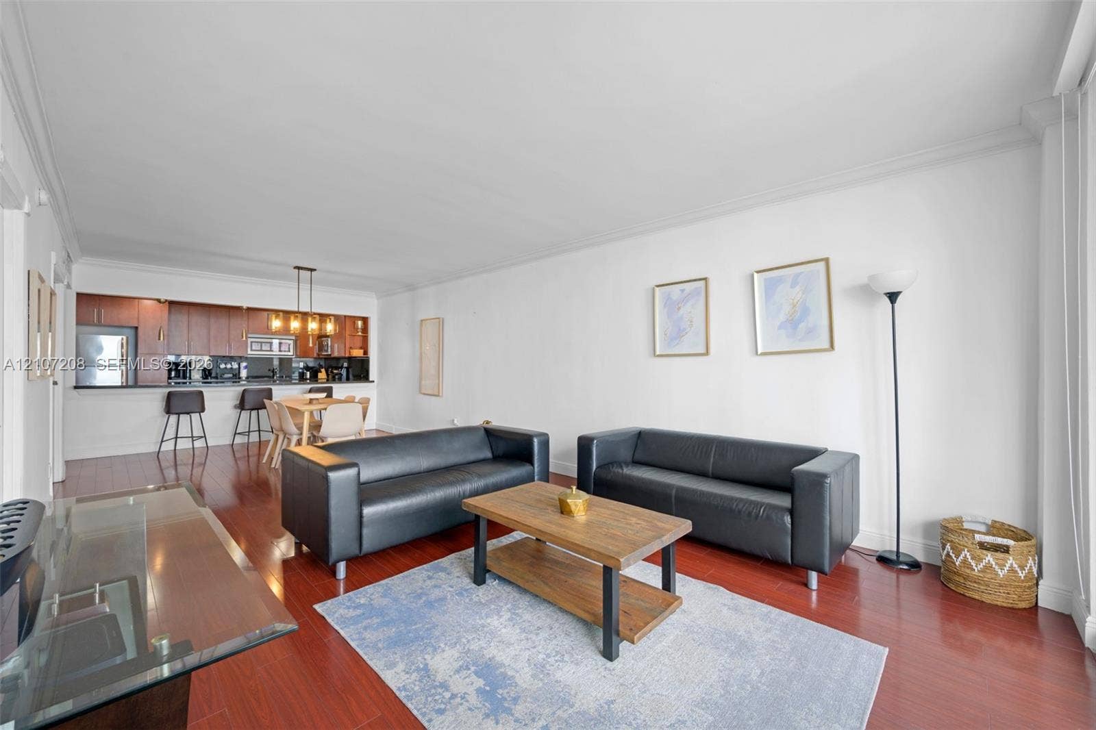 19370 Collins Avenue, #1405, Sunny Isles Beach, Sunny Isles Beach, FL 33160 Open-concept interior featuring wood-finish flooring, crown molding, and a kitchen with wood-finish cabinetry, a breakfast bar, and a pendant light fixture