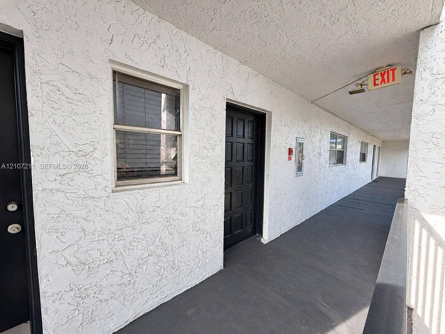 Textured stucco exterior wall with inset multi-pane entry doors and slider windows
