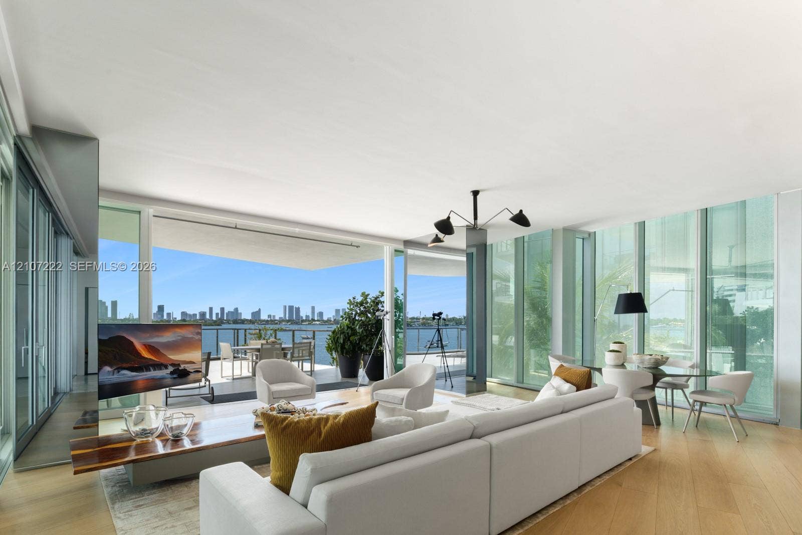 1300 Monad Terrace, #2F, Miami Beach, FL 33139 Floor-to-ceiling glass walls, wood-finish flooring, expansive covered balcony, and modern multi-arm ceiling fixture