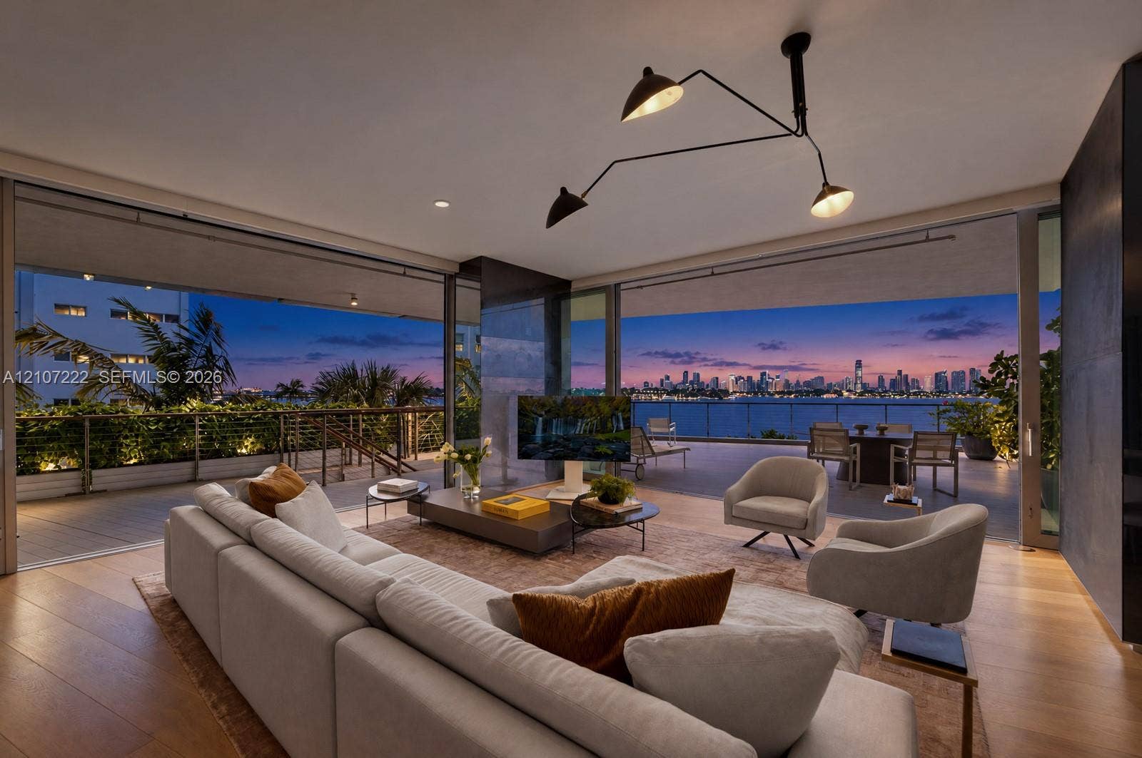 1300 Monad Terrace, #2F, Miami Beach, FL 33139 Open-concept living space featuring wood-finish flooring, expansive floor-to-ceiling glass sliding doors, a recessed balcony, and a multi-arm architectural pendant light